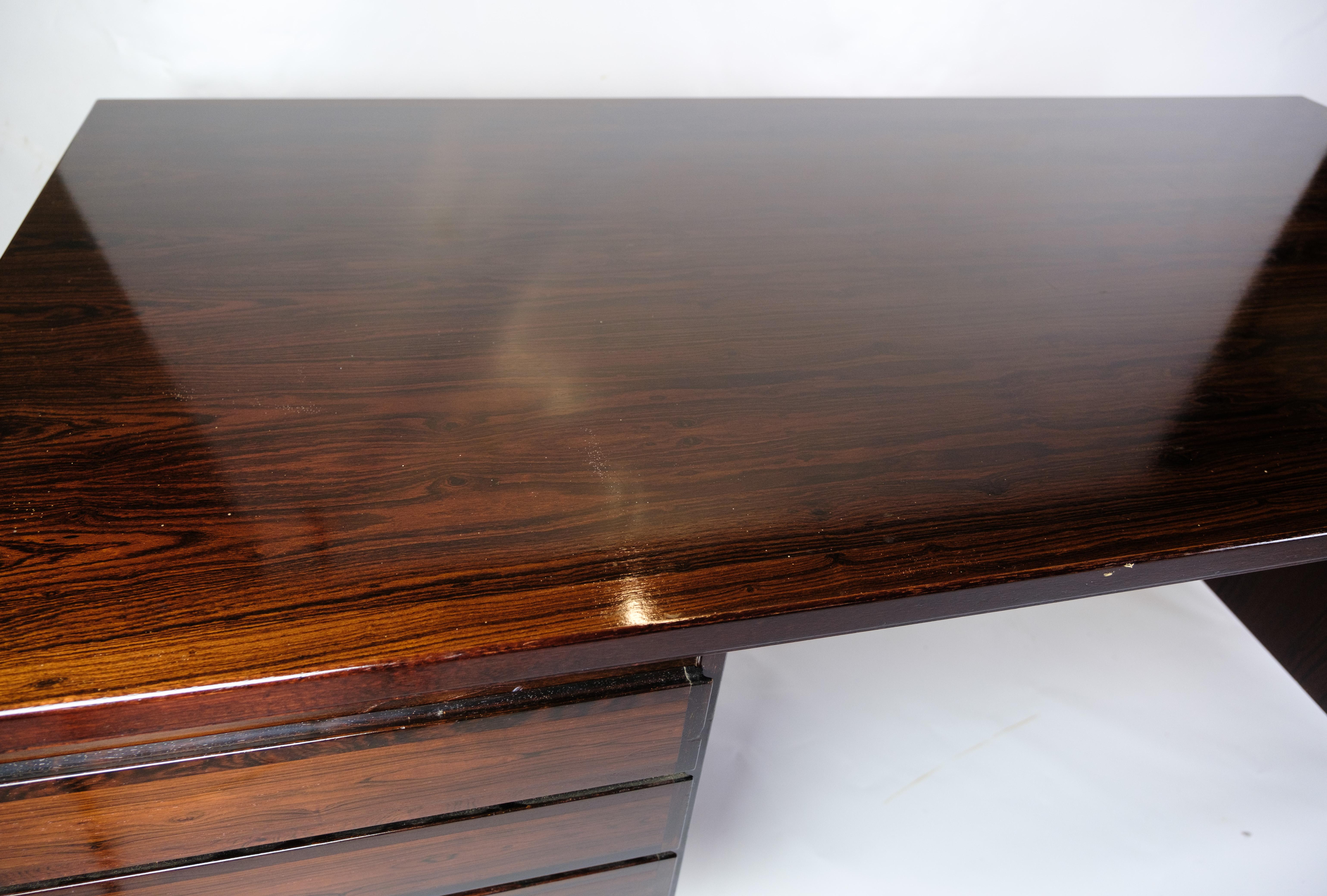 Ce bureau est un bel exemple de design danois des années 1960, créé par Omann Junior Møbelfabrik. Fabriqué en bois de rose de haute qualité, il dégage une élégance intemporelle et une finesse artisanale.

Derrière cette merveille de bureau se trouve