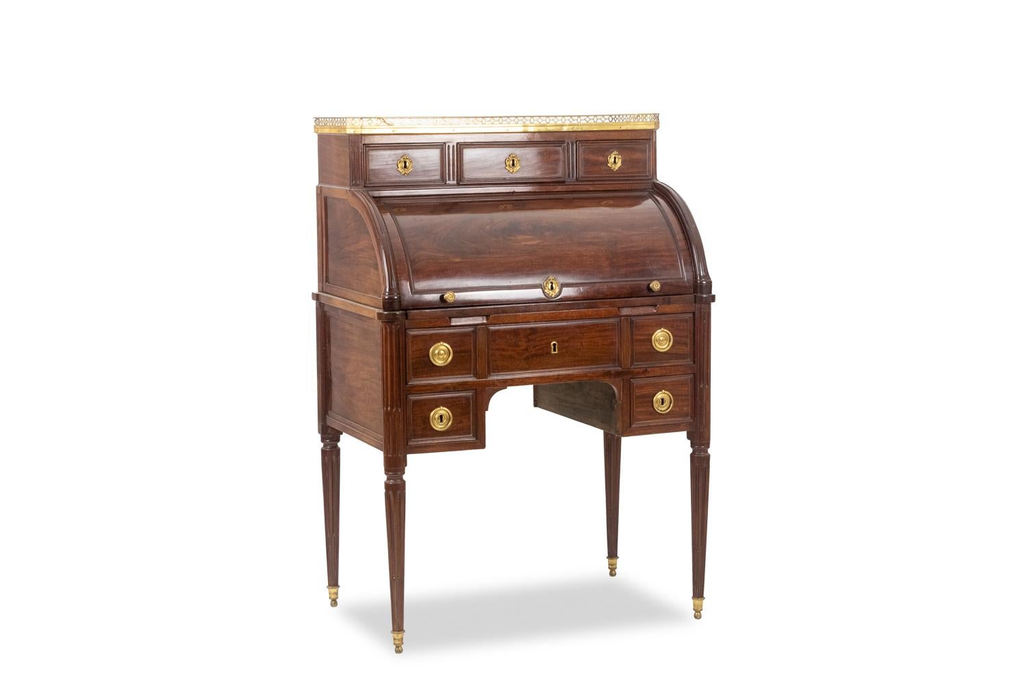 Desk – or secretary – with cylinder, in mahogany. The body opens with two small handles decorated with gadroons to a convex quarter-cylinder flap revealing a paper holder with in the center three small drawers covered in green leather with its fine
