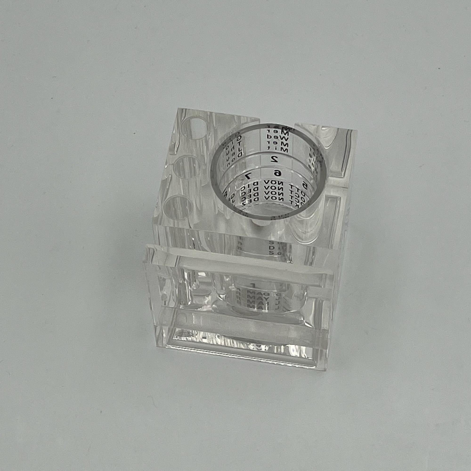 Stylish desk organizer with perpetual calendar made of plexiglass, designed by Fabio Manlio Ciocca and produced by Guzzini in the 80s.

This lovely vintage piece has a rigorous square shape that holds an ingenious perpetual calendar, made of four