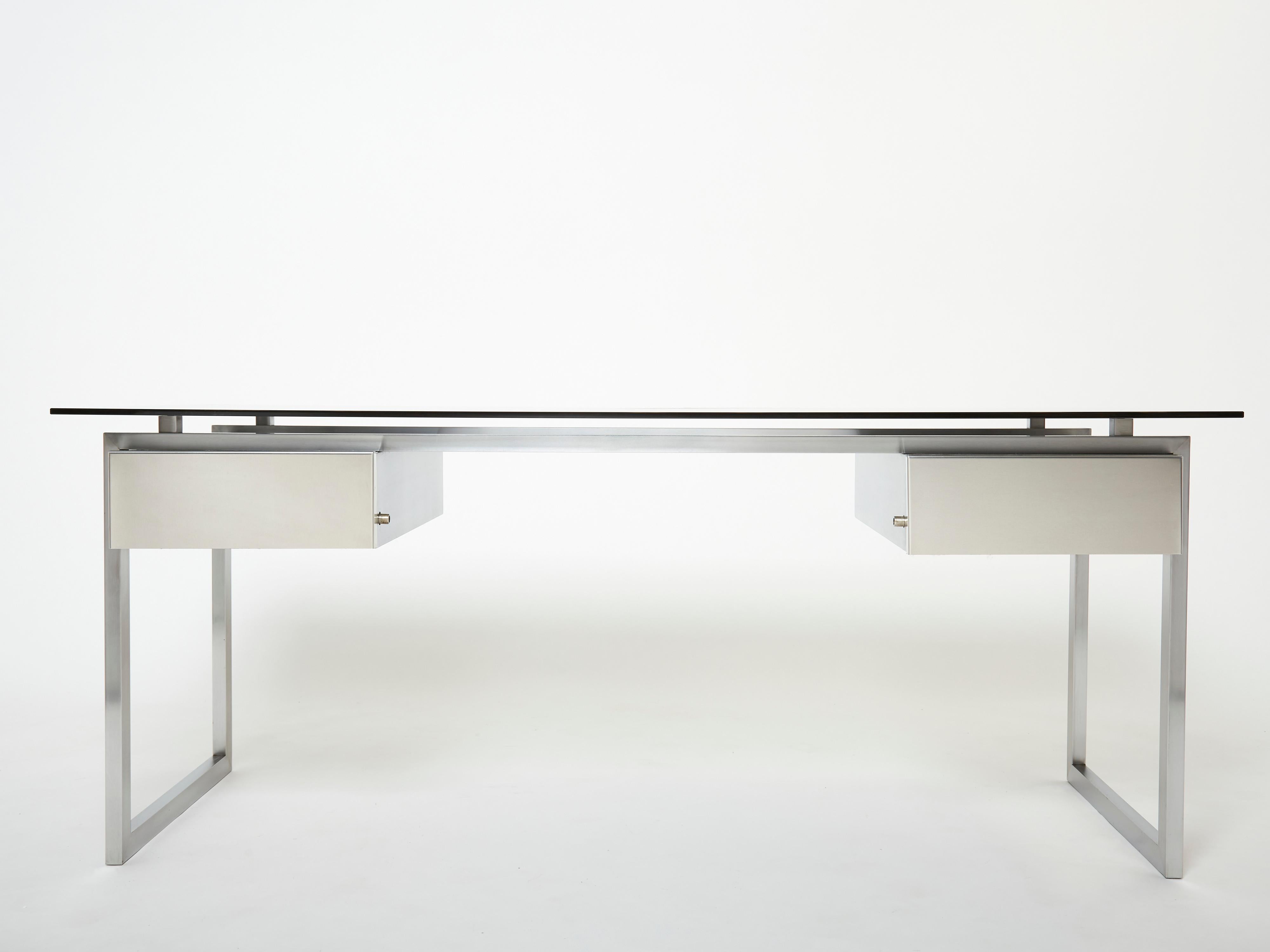 A rare brushed stainless steel desk table designed by French designer Patrice Maffei for Kappa editor in the 1970s, it features two locking drawers and a grey smoked glass top. Following the 1970s stainless steel trend, led by Maria Pergay, this