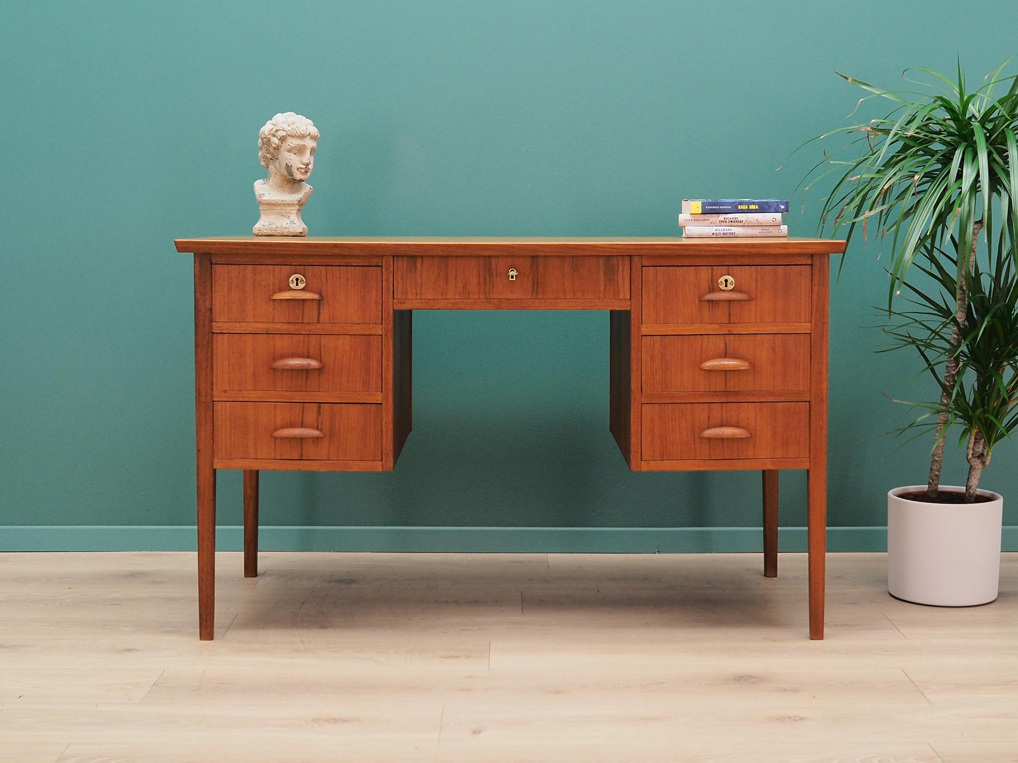 Desk made in the 1960s, Danish production.

Structure and top are covered with teak veneer. Legs are made of solid teak wood, perfectly integrated into the structure of the desk. Surface after refreshing. Front of the desk has seven drawers. It
