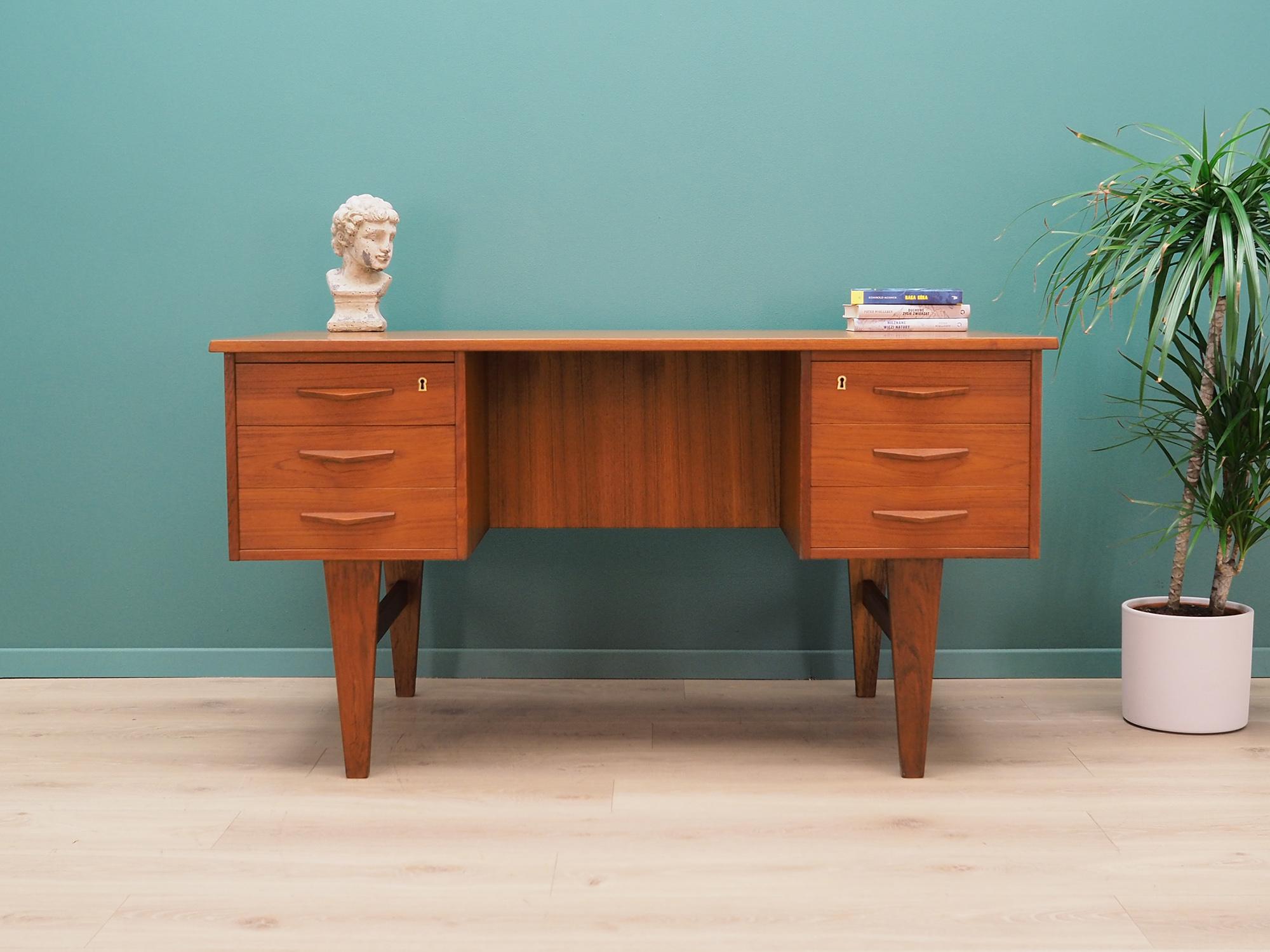 Desk made in the 1960s, Danish production.

The structure and top are covered with teak veneer. The legs are made of solid teak wood, perfectly integrated into the structure of the desk. The surface after refreshing. The front of the desk has six