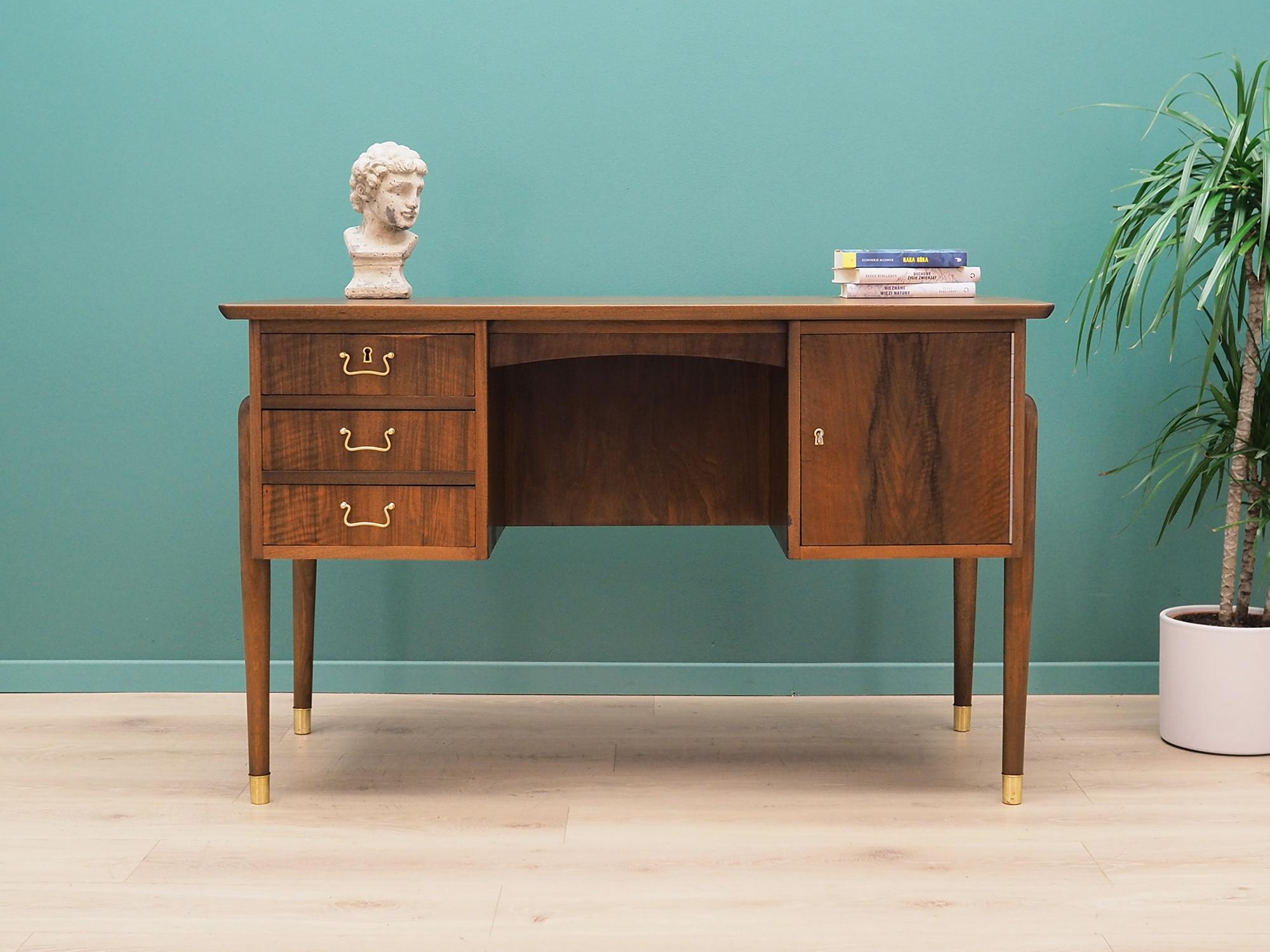 Desk made in the 1970s, Danish production.

The structure and top are covered with walnut veneer. The legs are made of solid walnut wood, perfectly integrated into the structure of the desk. The surface after refreshing. The front of the desk has