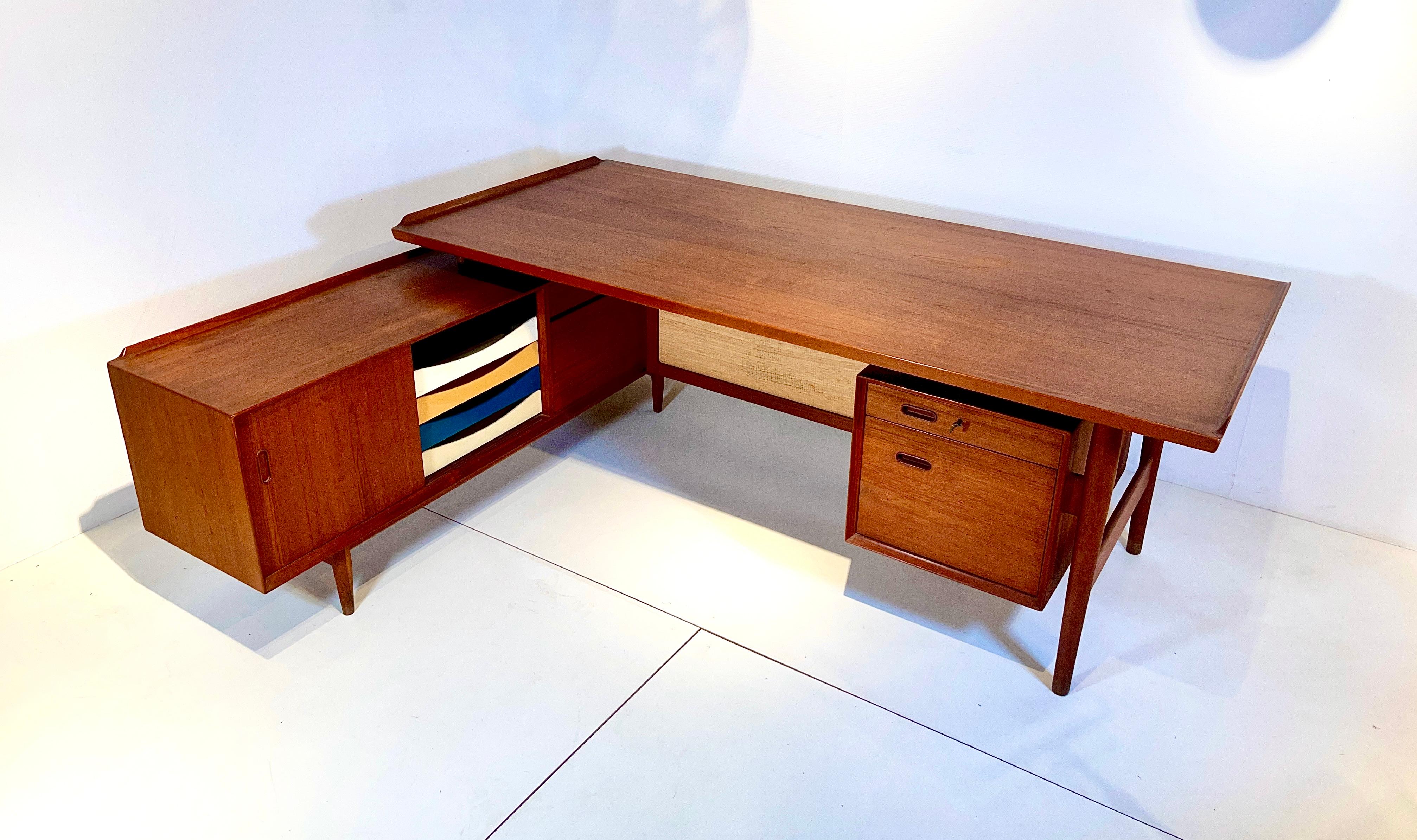 An iconic high end desk with sideboard, designed by Arne Vodder in the 1950's. Made in teak with the original lacquered drawers in different colors and the seagrass separation panel, with key. Very good conditions with some traces of ware.