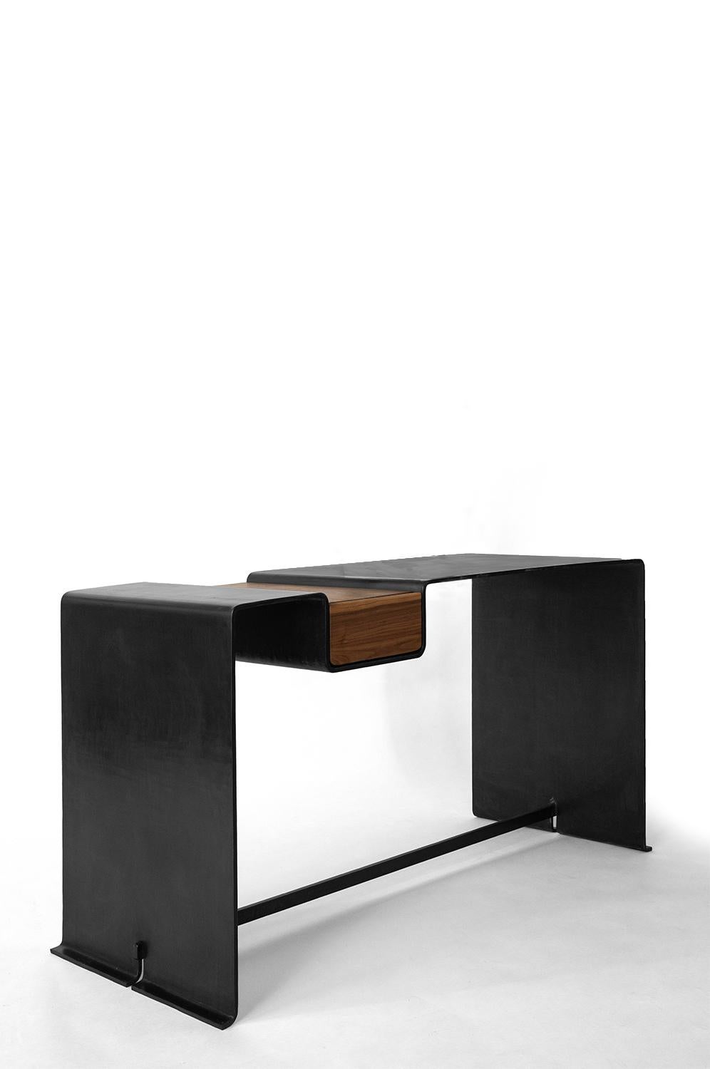 DESK NO. 1
J.M. Szymanski
d. 2023

With the combined power of our steel smith and the modern machine, this desk/vanity is hydrology bent from 3/8” thick solid steel. The table is hand finished in a rich and warm black patina. A modern classic for