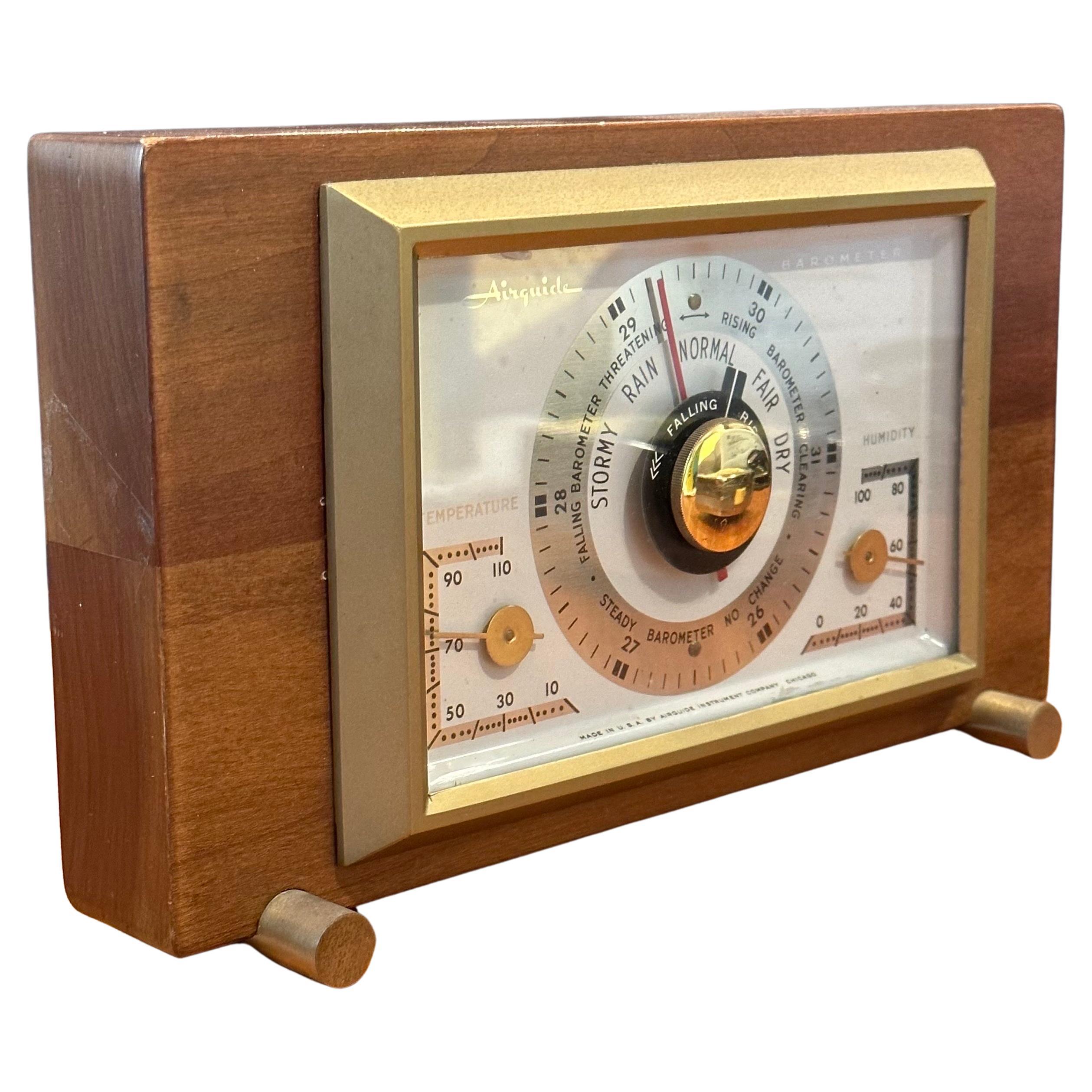 A very cool desktop barometer / weather station by Airguide Instrument Company, circa 1950s.  The device is packaged in a walnut case with brass feet and accents.  It has gauges and instuments to let you know the current temperature, humidity and