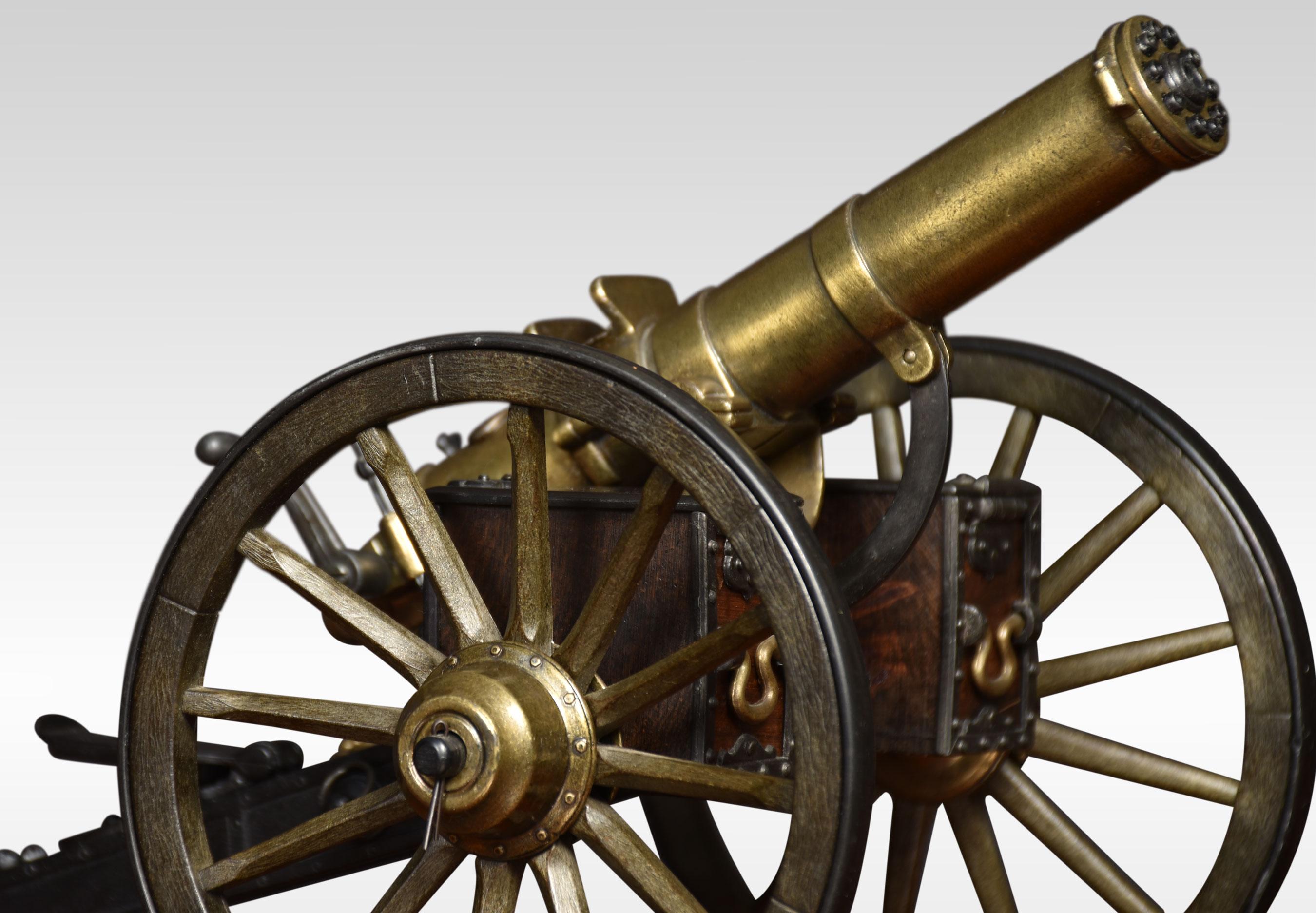 Desktop model of a Gatling field gun, the turned brass barrel set to a tilt mechanism on the painted metal carriage with brass bossed wheels, the working hand crank rotating the inner barrel to create a realist firing action, brass plaque stamped
