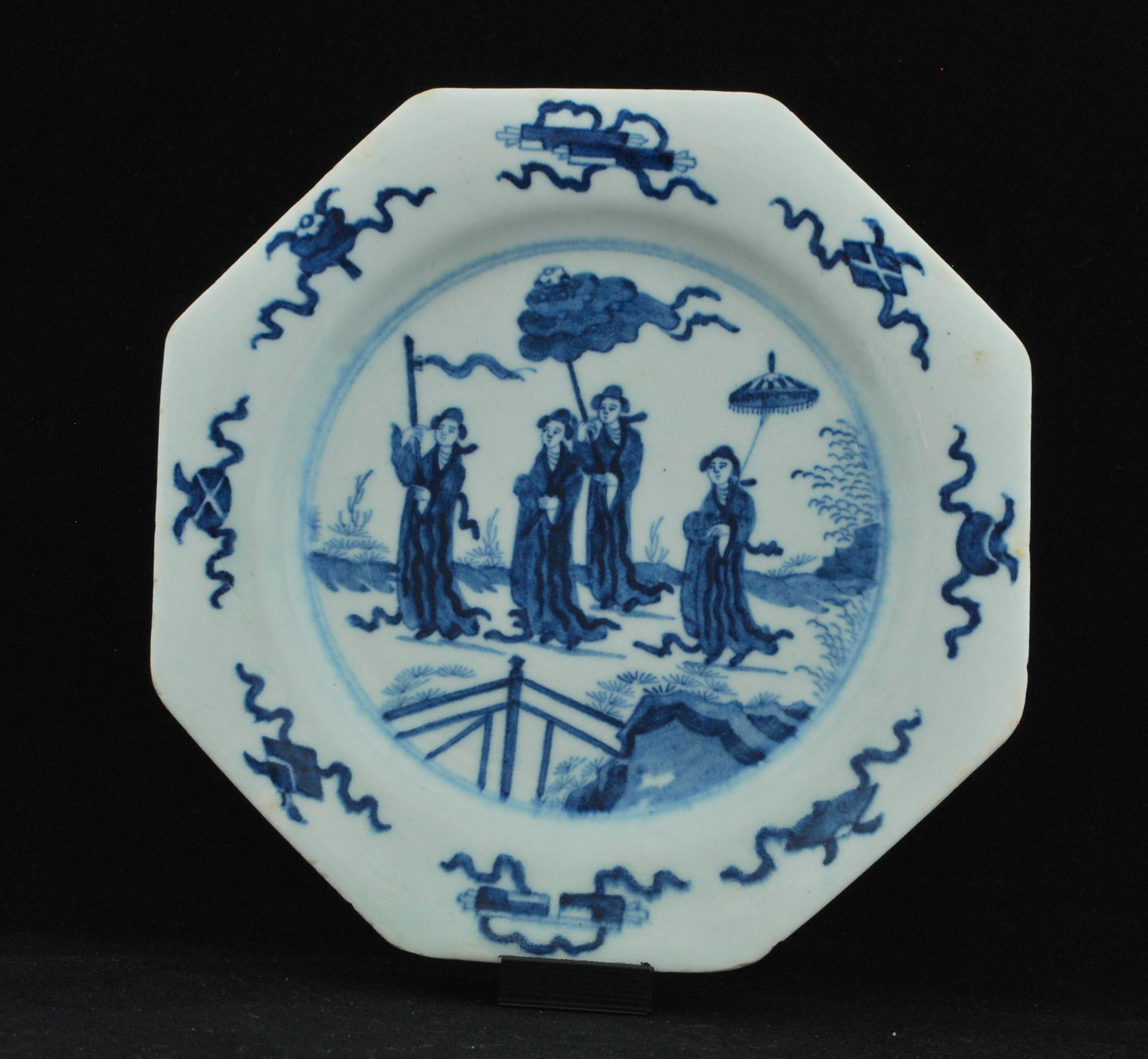 Plate, circa 1755-1760: Octagonal plate, the decoration after an oriental original (possibly from the region now modern Bhutan), with four robed ladies walking through a stylized landscape, the first with a Buddhist prayer flag, the third and fourth