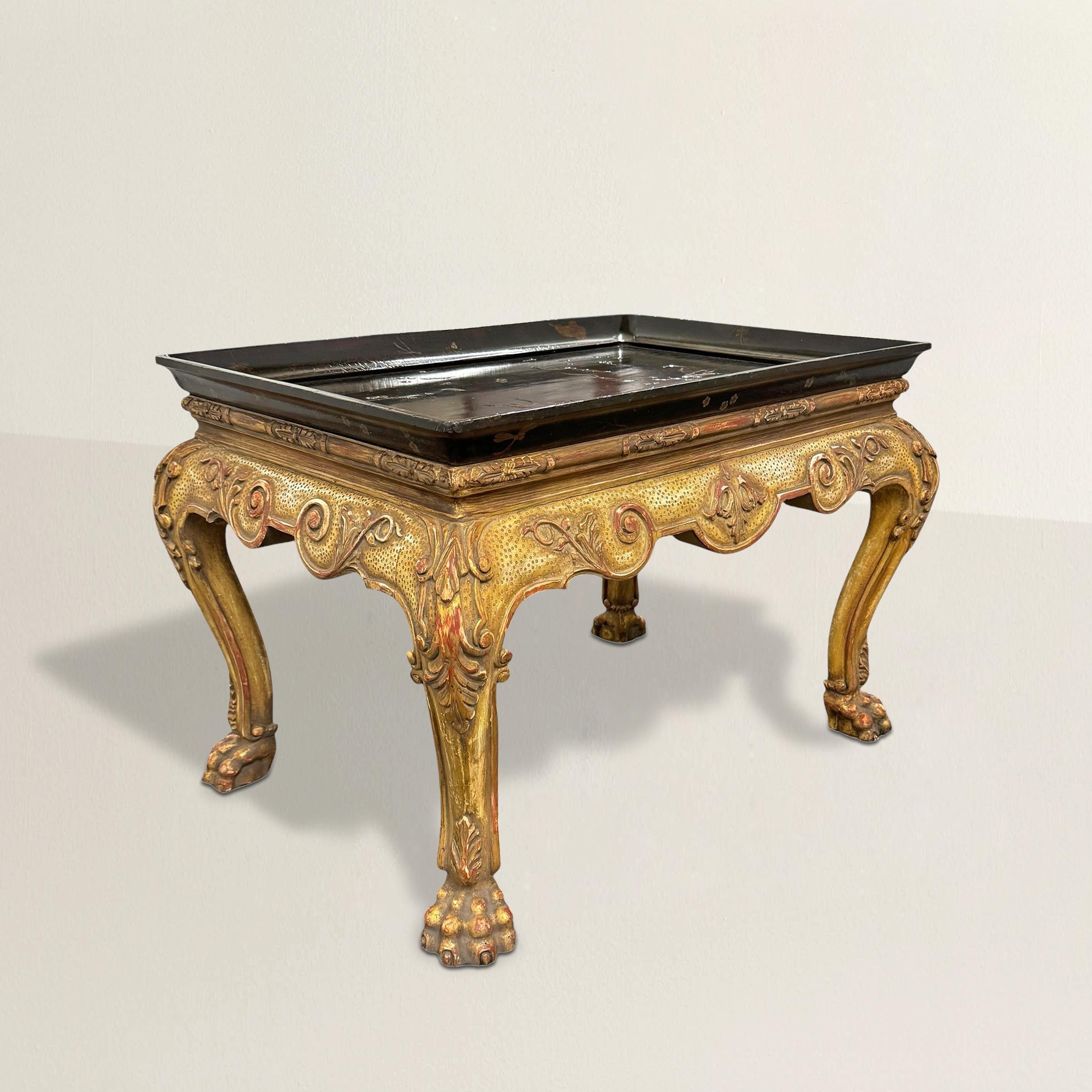 This early 21st-century Belgrave Tray Table by Dessin Fournir channels English Georgian grandeur with a touch of exotic flair. The base is richly carved, with bold cabriole legs ending in robust lion paw feet and a deeply scalloped apron adorned
