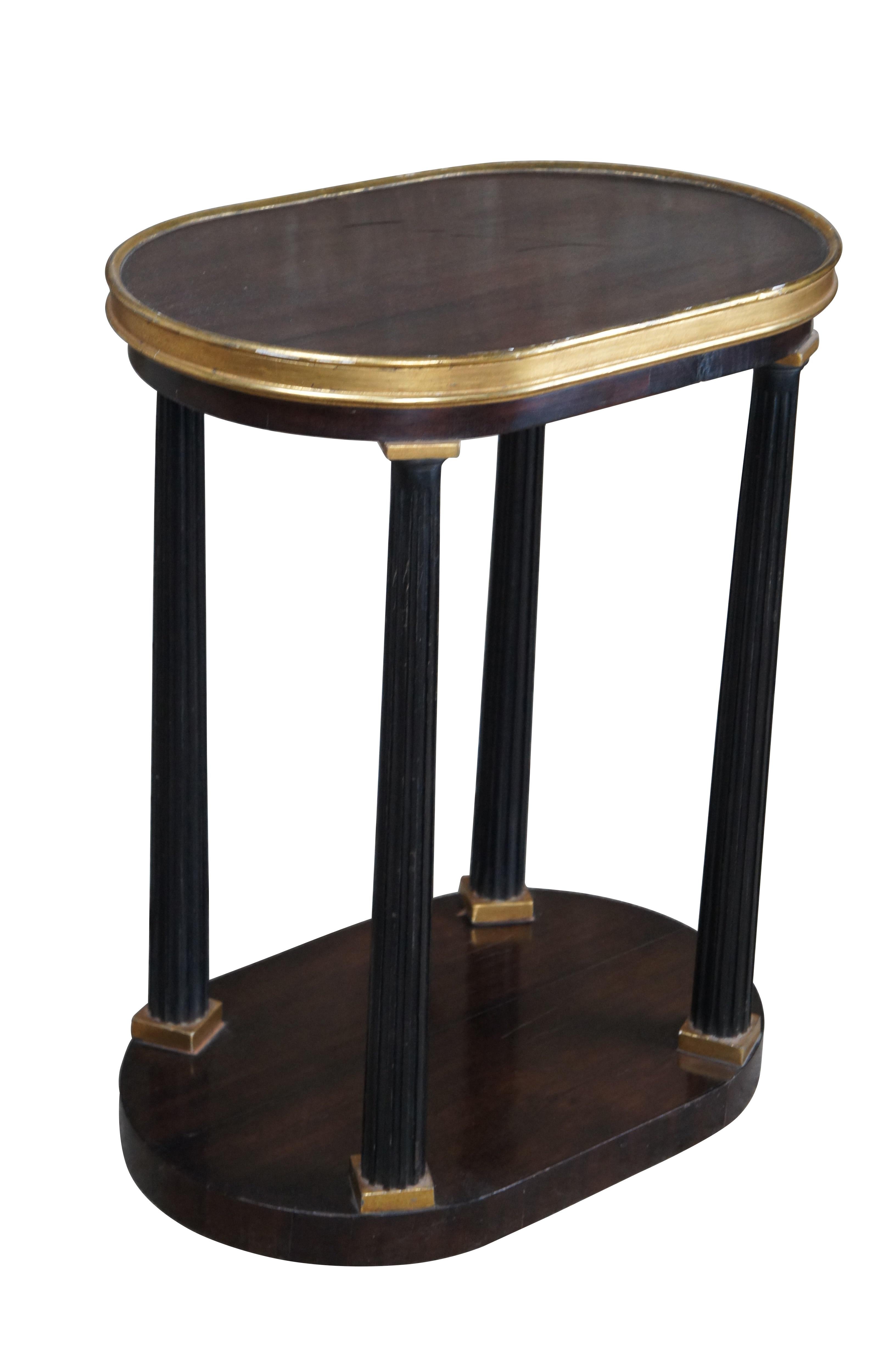 Dessin Fournir Romney Side Table, circa late 20th Century. Drawing inspiration from Louis XVI, Neoclassicism and Empire styling. Features an oval top made from mahogany with 22k gold leaf giltwood-trimmed tray edge over fluted ebonized columns and