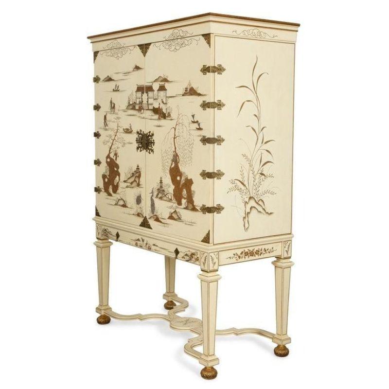 A monumental vintage Dessin Fournir white lacquer Griswold cabinet with brass hardware and intricate gold detail. The front of the piece has hand painted Chinoiserie scenes of people fishing and playing with other details like pagodas, landscape and