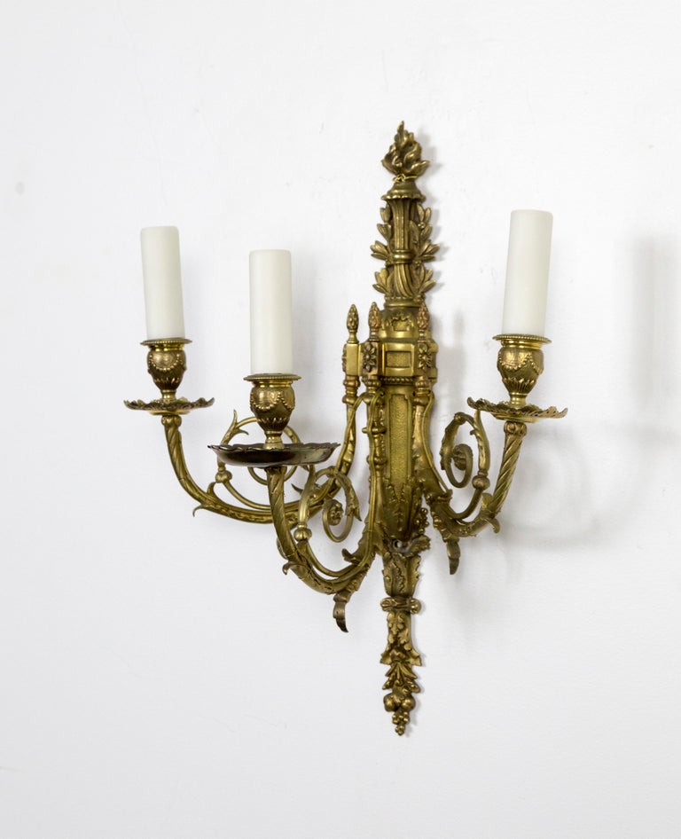 A pair of brass, 3-arm wall lights in the 2nd Empire style. Encompassing many Neoclassical Revival elements; swagged, urn candle cups, acanthus leaf arms, plumed backplate, reeding, foliate scrolls, bountiful fruit flourishes and flamed topknots,