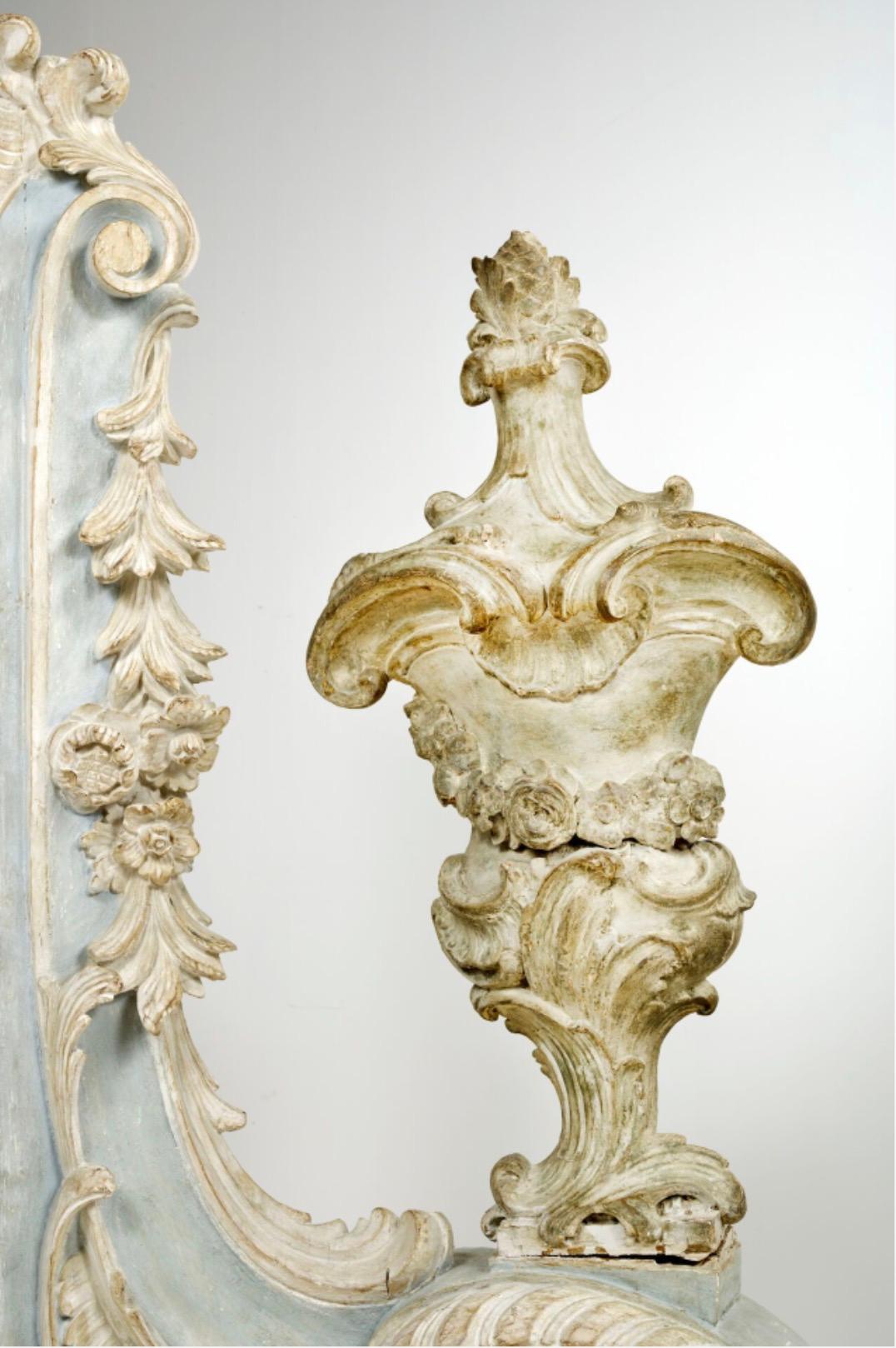 Paire de boiseries décoratives d'entrée représentant l'un amour assis et l'autre un vase. La base sculptée est constituée d'arabesques dans un motif de feuillage. L'ensemble est laqué d'une couleur blanche et bleue pâle.