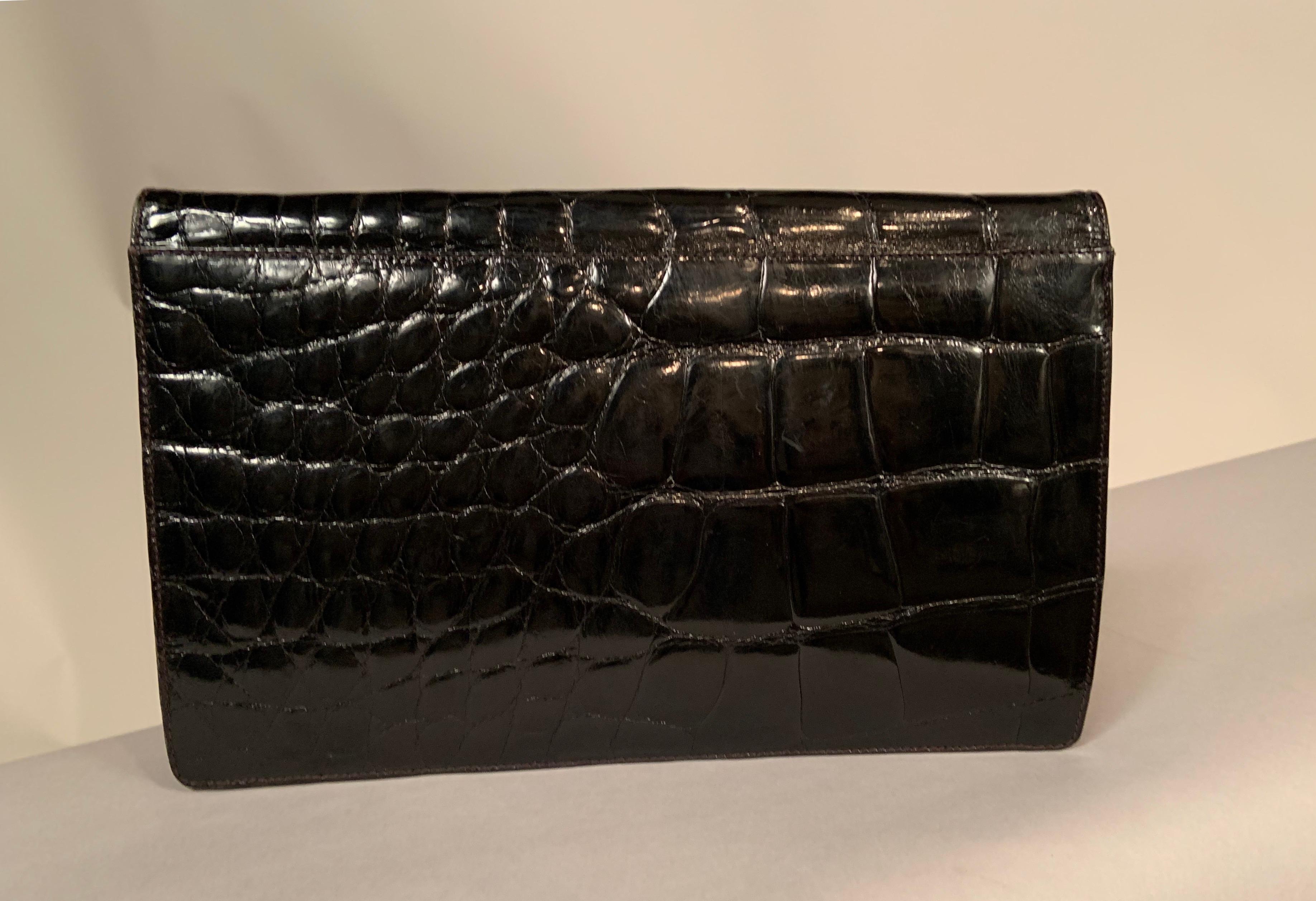 Chic and sleek this large black American alligator clutch will hold all of your necessities. The bag has a hidden snap 
closure, a black leather and suede interior, an optional black alligator shoulder strap and one slip pocket and one zipper pocket