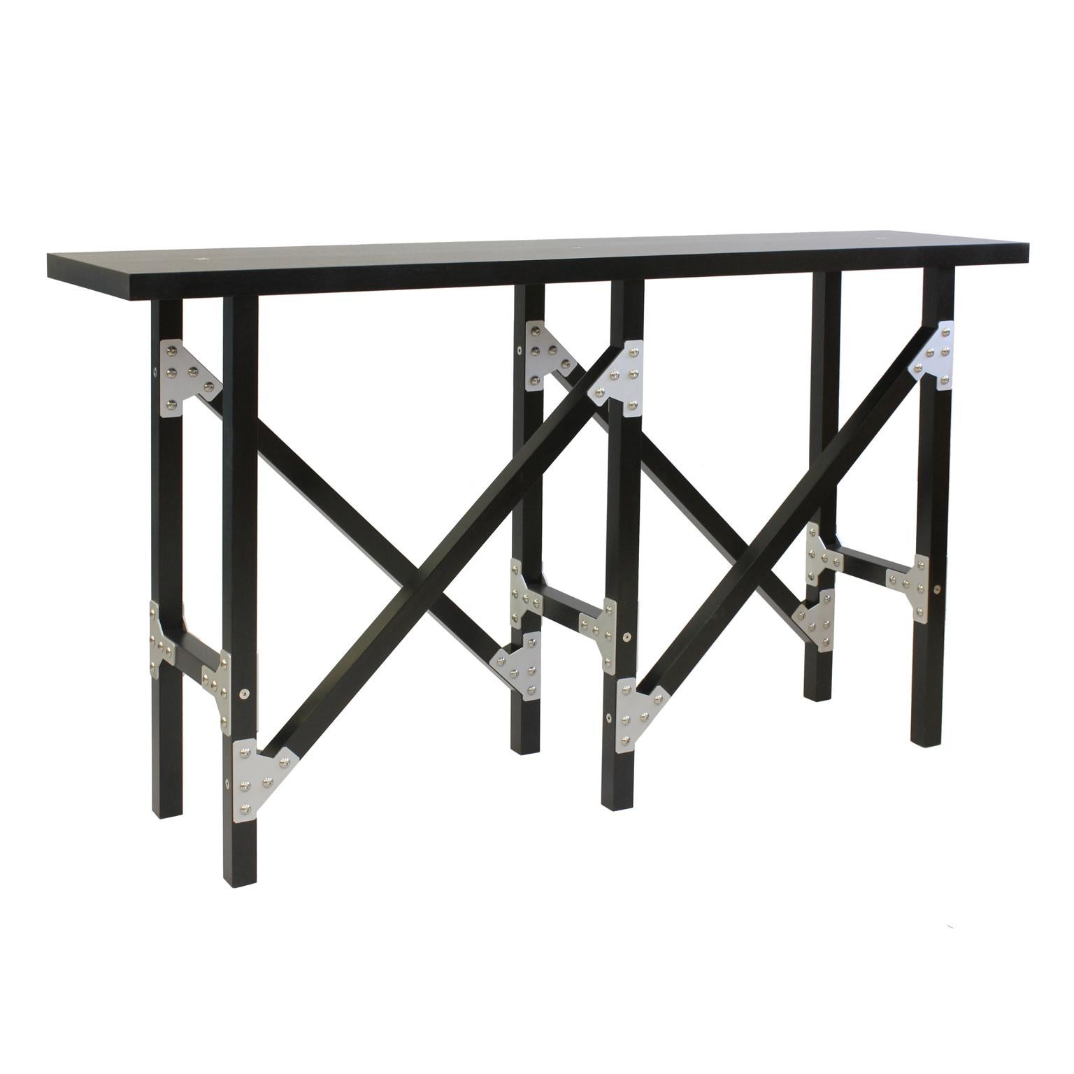 This table continues my exploration of the power of wooden line-like elements and industrial metal bracketry. It introduces the concept of a 45 degree line contrasting against its six vertical legs. The top is punctuated by three polished stainless