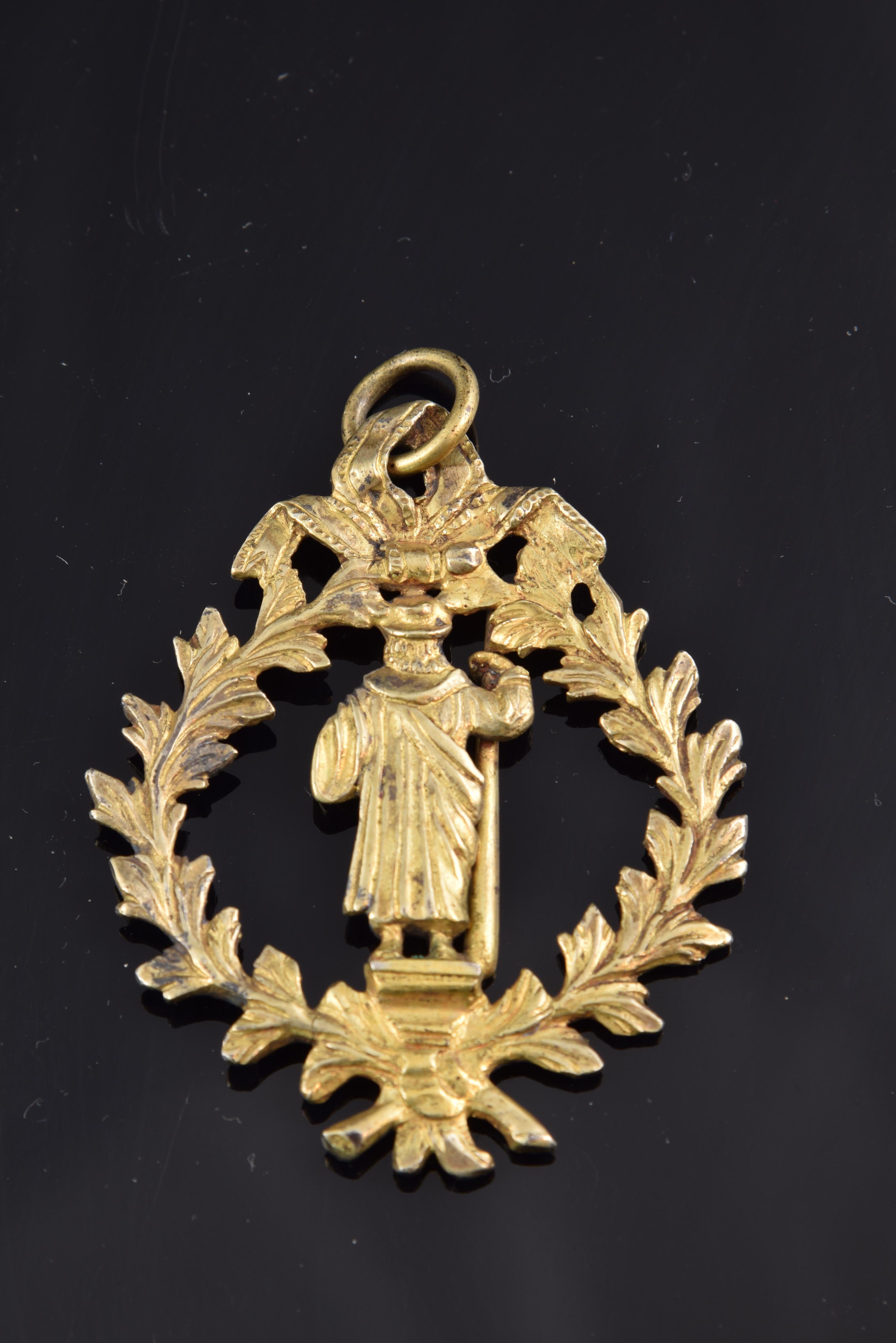 Devotional medal, Santiago Apóstol. Ormolu, 17th century.
 Openwork devotional medal with the image of Santiago Apóstol in the center, on a pedestal and holding a staff and a book, surrounded by a crown of leaves knotted with two loops above and