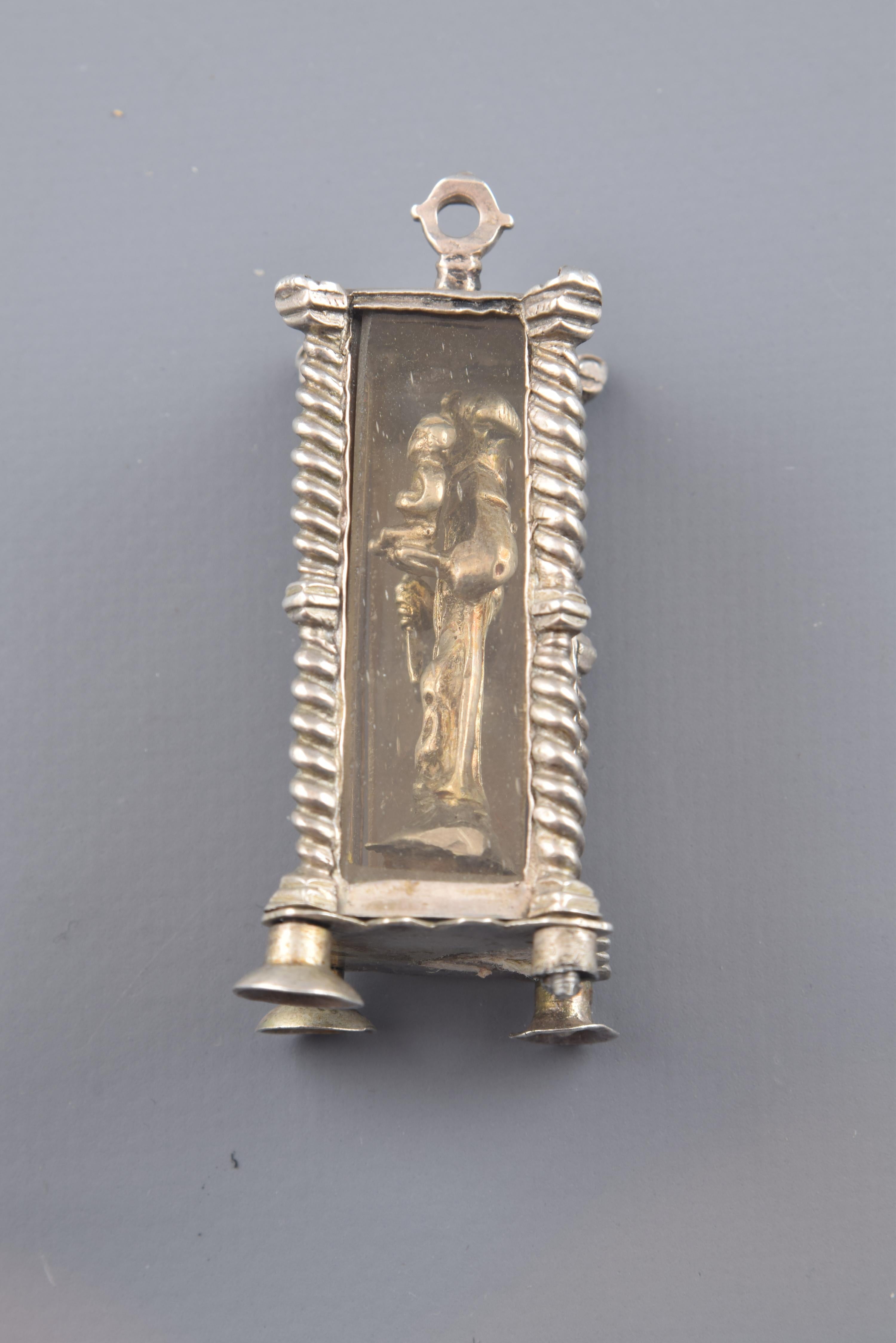Pendant in the shape of a chapel or square altar with legs and four columns on the corners, enhanced with a central polygonal dice that repeats the lines of the base and the capital of the same. It has sheets of transparent glass on its four fronts,