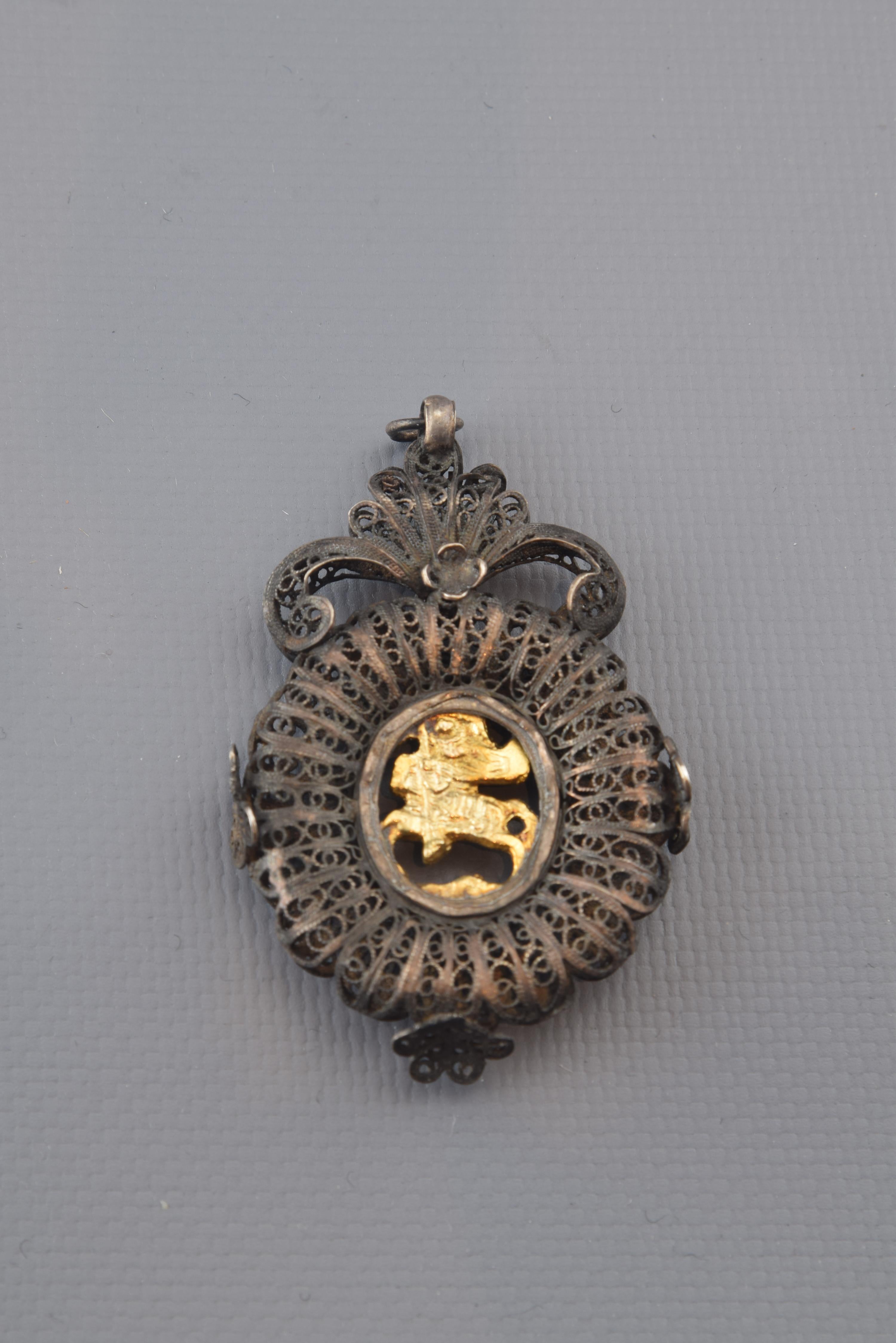 Devotional pendant with St. George. Silver filigree and gilt silver. 19th century.
Silver filigree pendant in its color with a top shell-like-decorated (