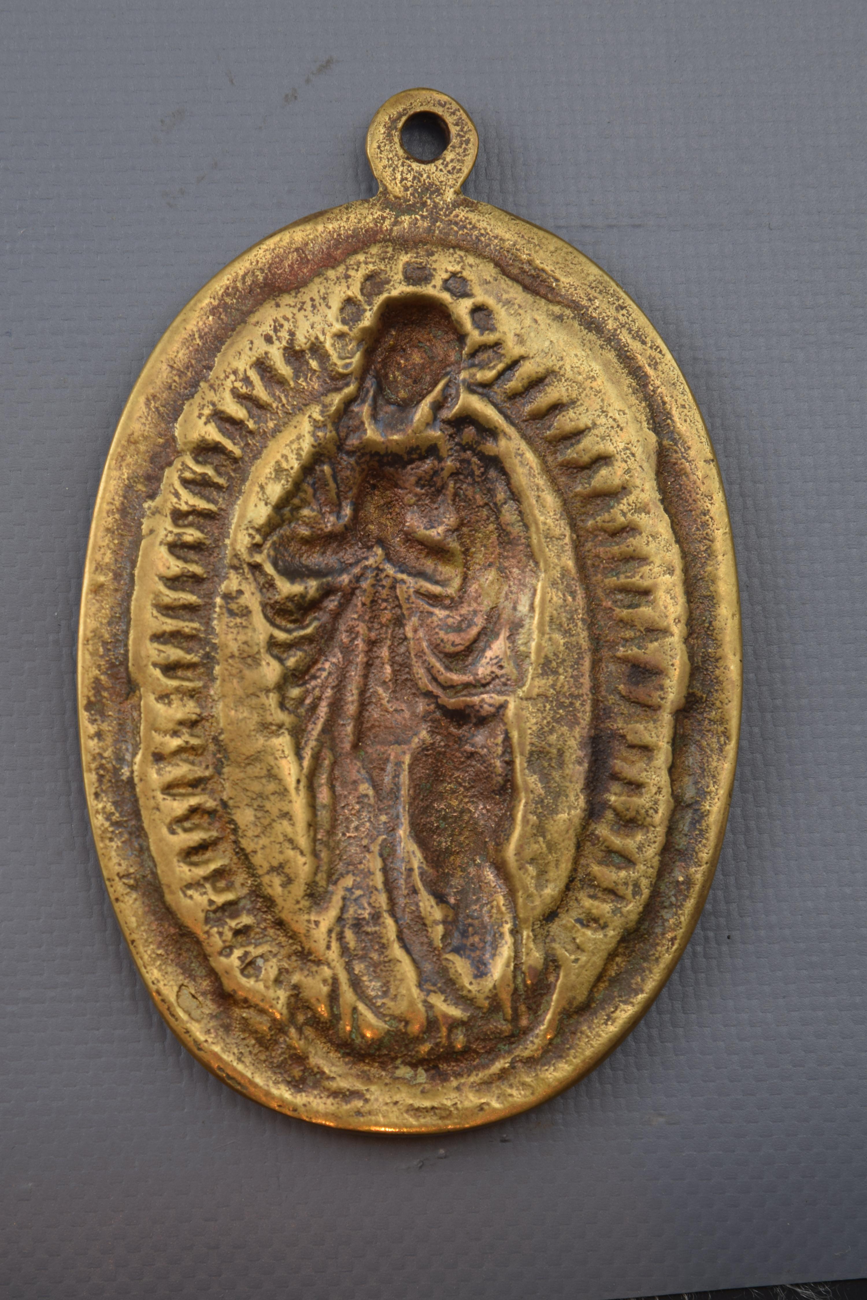 Devotional plaque, immaculate bronze, 19th century.
Devotional plate made of oval-shaped bronze, which has a ring on the top and a simple frame enhancing the relief of its forehead. With the Franciscan cord around it, the immaculate figure is