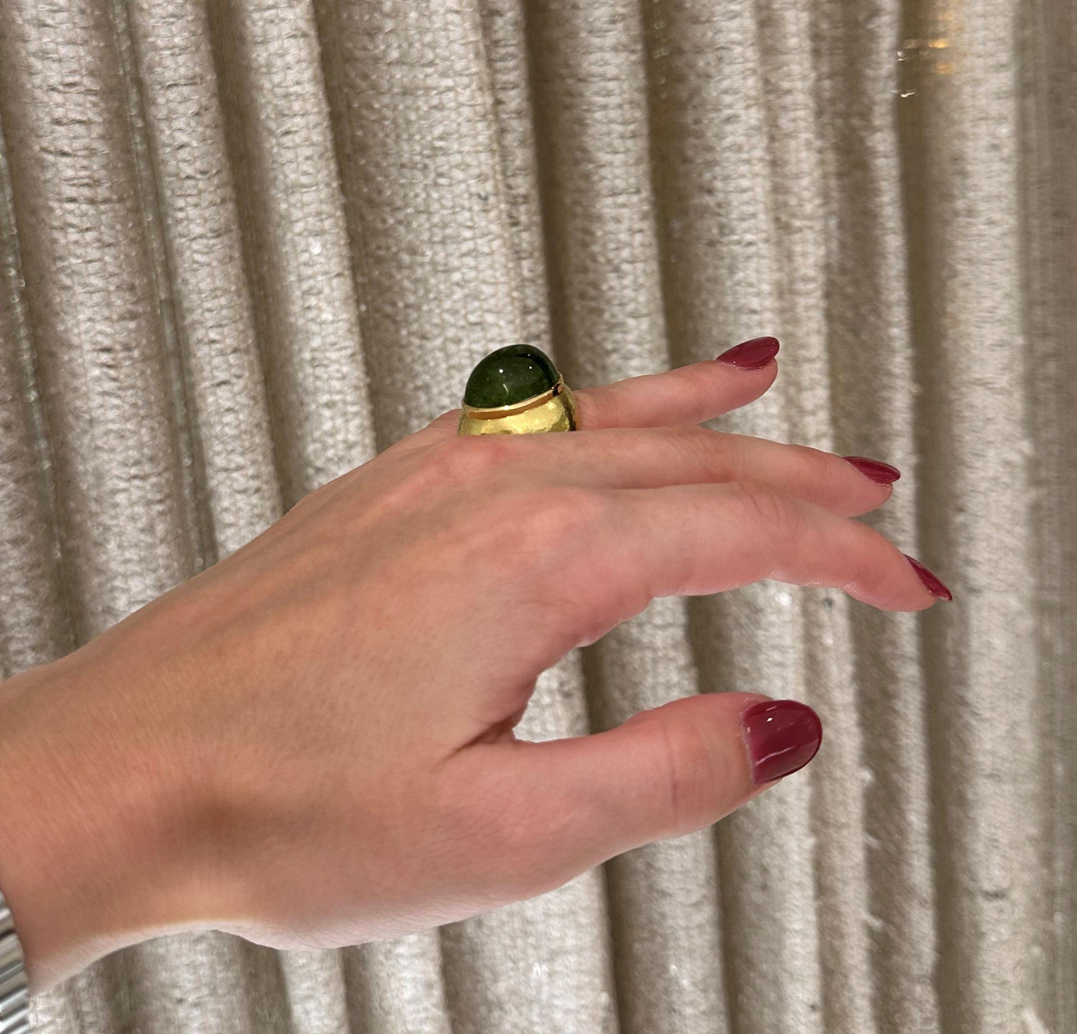 From the Eiseman Estate Jewelry Collection, this circa 1980's 18 karat yellow gold ring by designer DeVroomen is set with an approximately 16.5 carat green tourmaline cabochon. The ring has a hammered finish and measures 24.73mm wide along the top