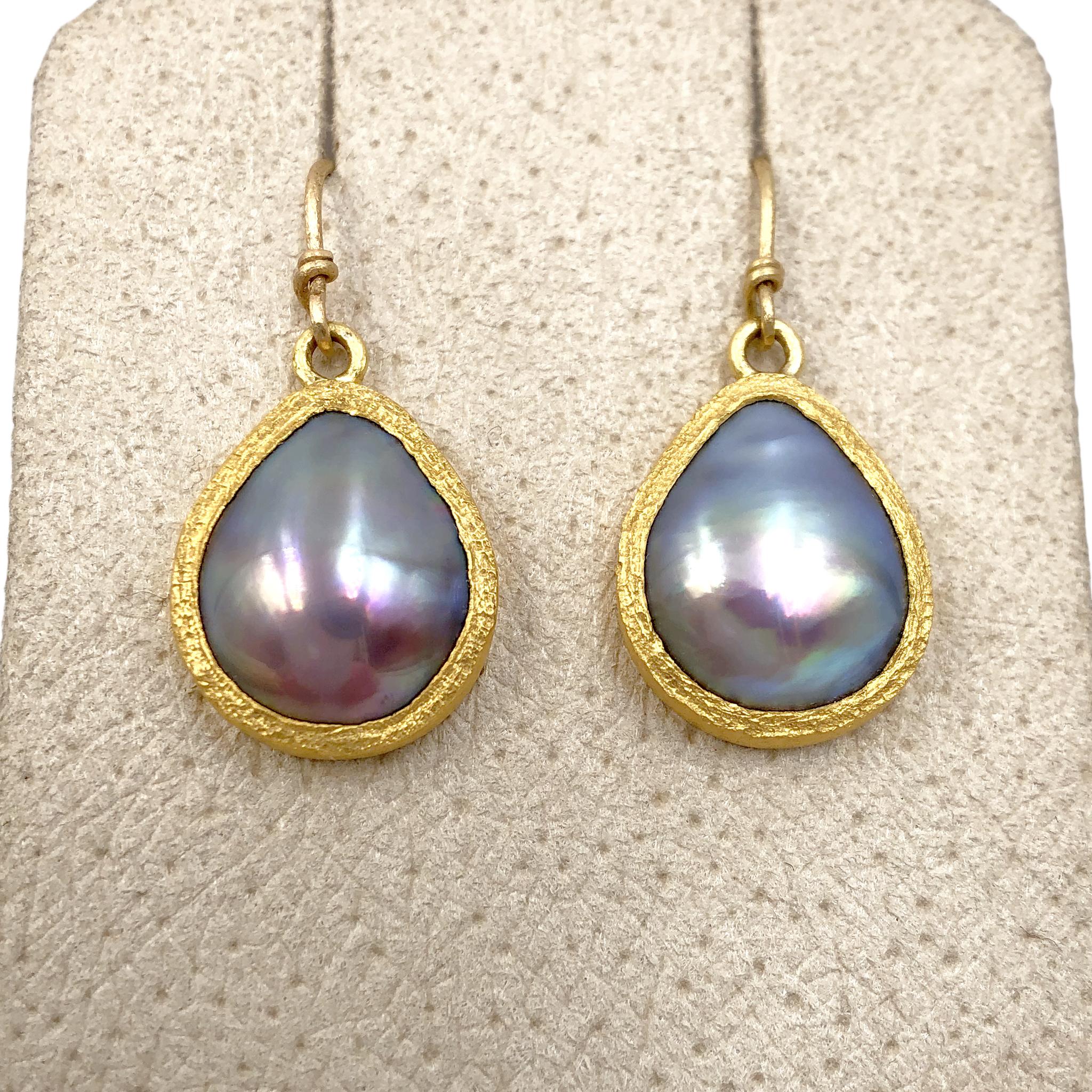 One of a Kind Drop Earrings handcrafted by acclaimed jewelry maker Devta Doolan featuring a stunning matched pair of mabe pearls from the Sea of Cortez, exhibiting a violet-blue base color with electrifying iridescence. The pearls are bezel-set in