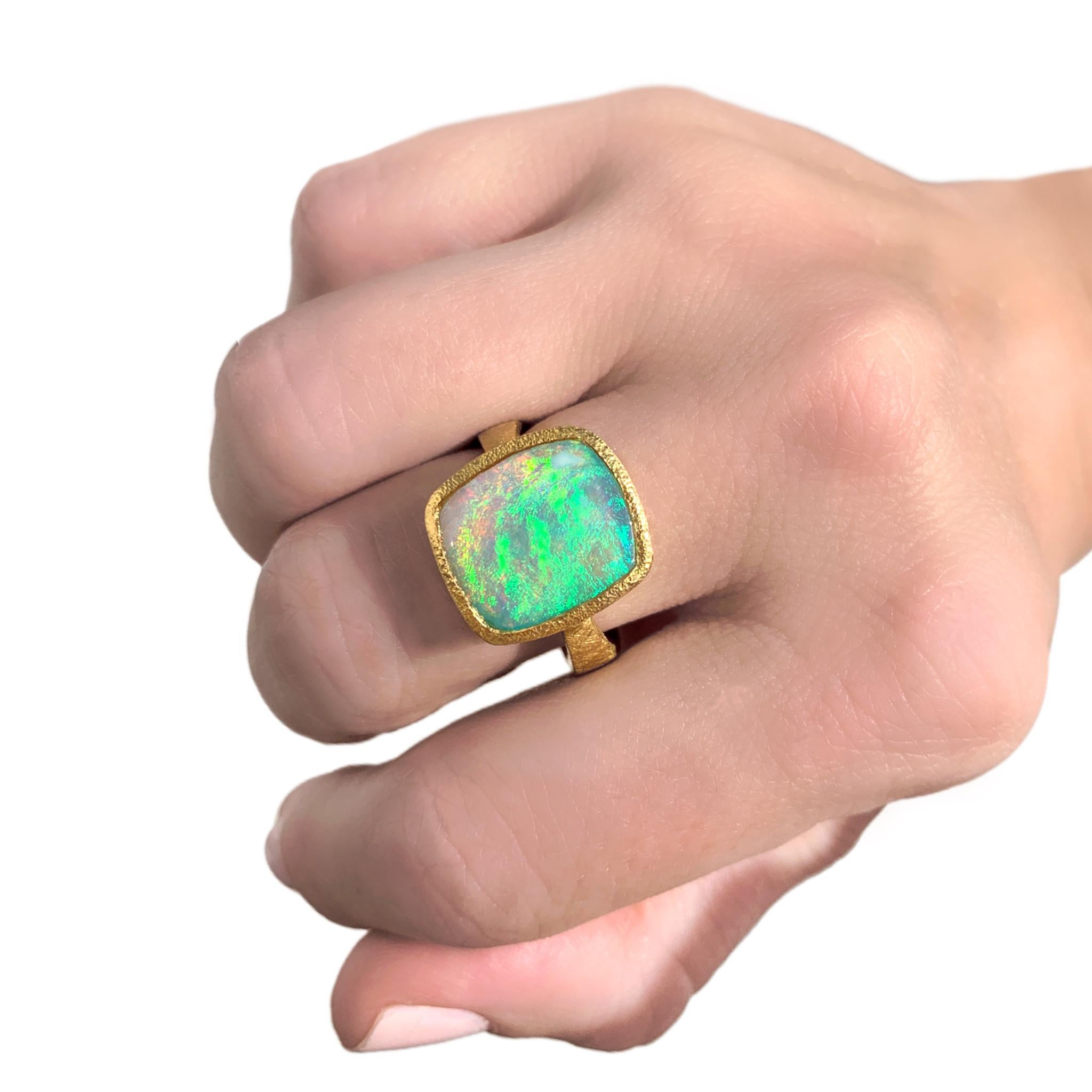 One of a Kind Ring by acclaimed jewelry maker Devta Doolan showcasing a spectacular cushion shaped Australian Lightning Ridge crystal opal, electrified by a bold green flash and full spectrum rainbow color-play. The gem opal is bezel-set in the