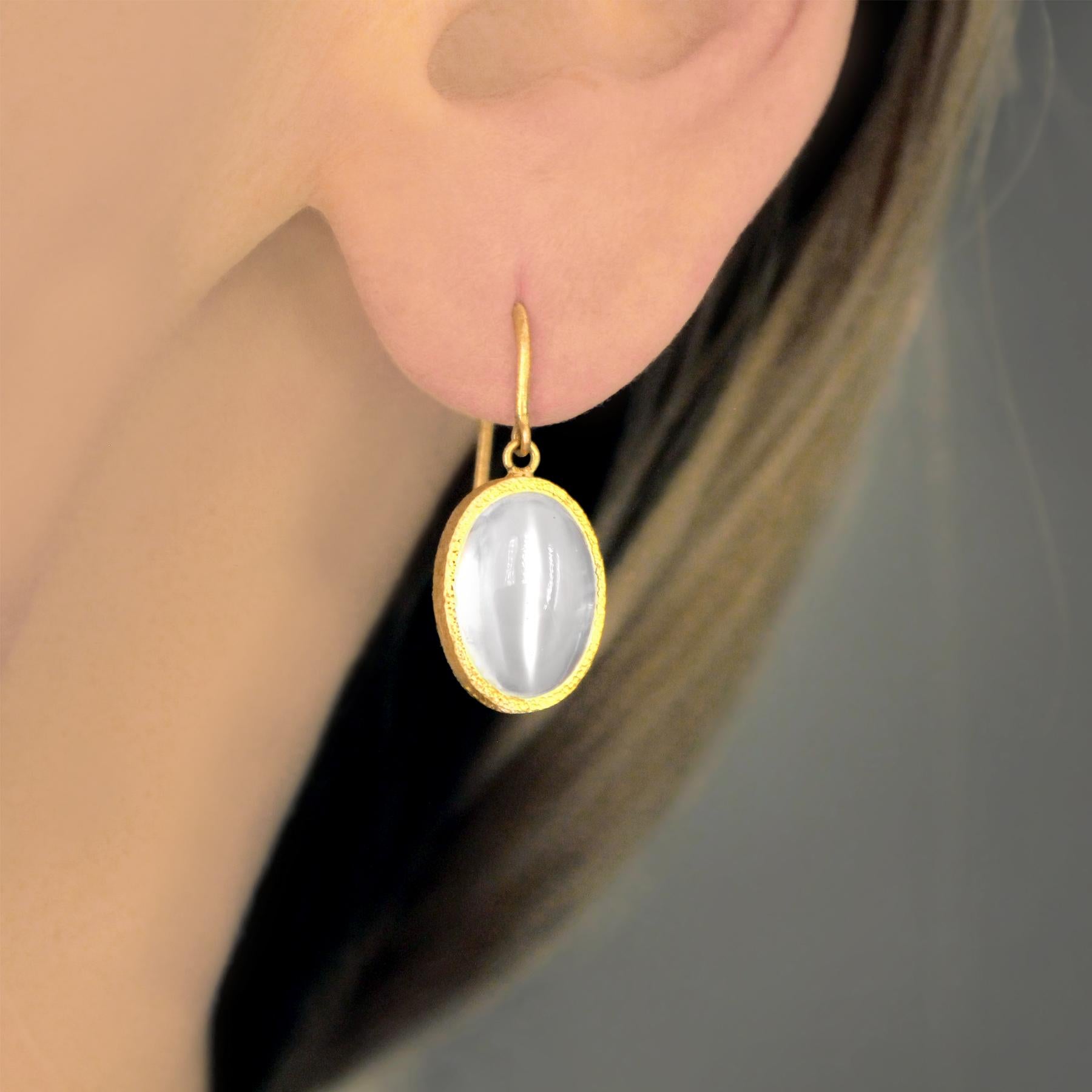 One of a Kind Drop Earrings hand-fabricated by jewelry maker Devta Doolan in signature-finished 22k yellow gold showcasing a spectacular matched pair of oval, cabochon-cut silver cat's-eye moonstones with strong adularescence. Stamped 22k with the