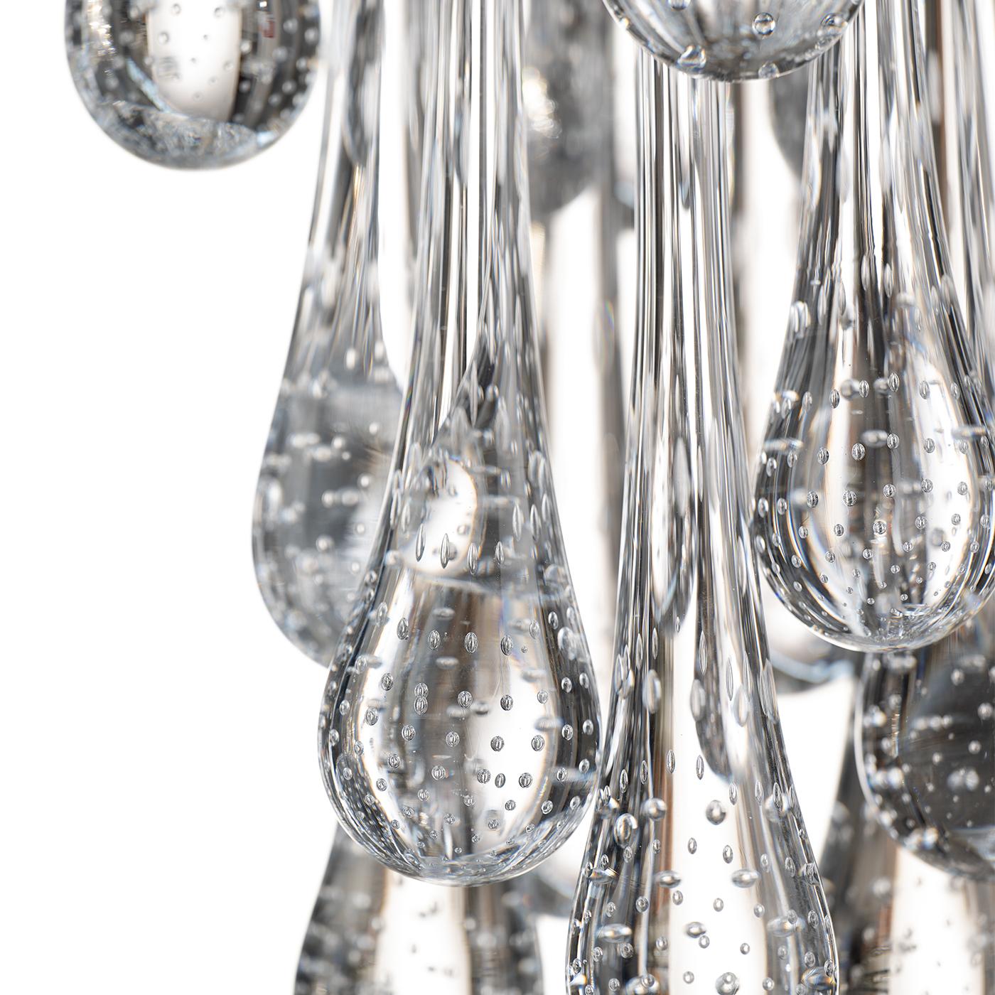The poetic image of a dewy lane just before daybreak inspired this stunning chandelier. Mounted on a glistening golden-finished metal frame, three tiers of drop-shaped Murano glass elements splendidly diffuse the light, an effect enhanced by tiny