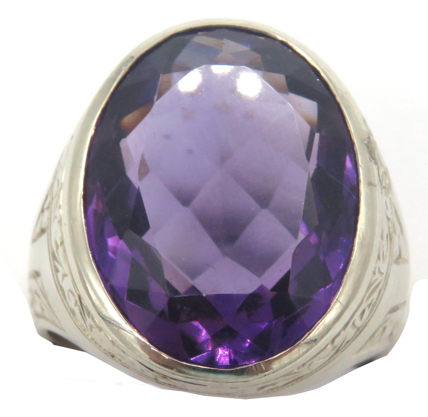 A beautifully faceted oval amethyst gemstone set in a 14k white gold setting. Engravings appear around the top and sides of the white gold band. The ring measures 1.25 inches high and 0.75 inches wide. Simple yet stunning, this is a versatile piece