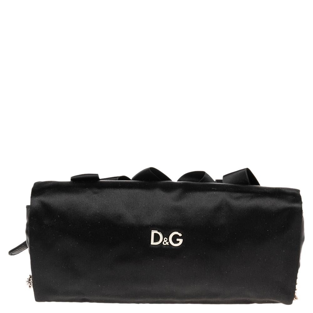 This feminine clutch from D&G is a perfect piece to carry to that evening party. It has been crafted from fine quality satin and has a deep rich black color. It has a front flap that is adorned with ribbon detailing. A leather & satin-lined interior