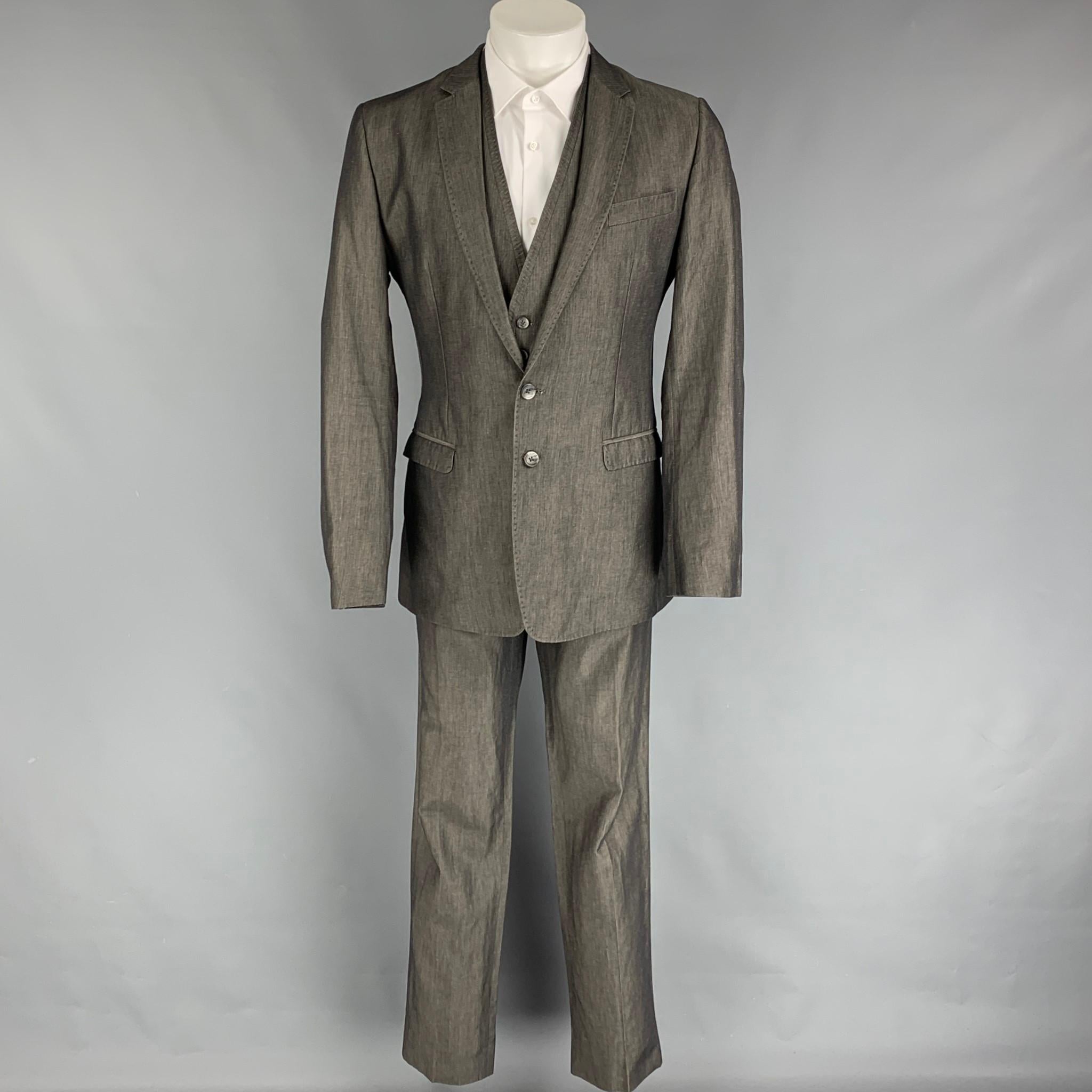 D&G by DOLCE & GABBANA 3 Piece suit comes in grey cotton / linen with a full liner and includes a single breasted, double button sport coat with a notch lapel and a matching vest and flat front trousers. Made in Italy.

Very Good Pre-Owned