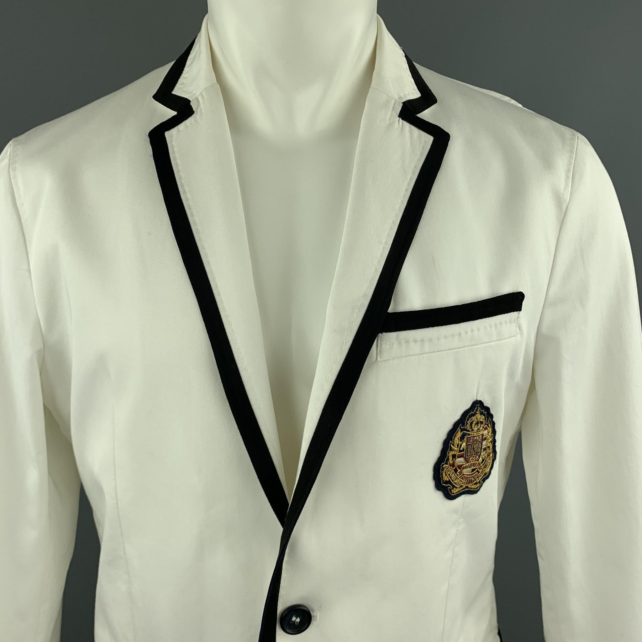 D&G by DOLCE & GABBANA blazer comes in light weight cotton blend twill with a notch lapel, single breasted, two button front, navy faille piping, and embroidered chest patch. Made in Italy.

Very Good Pre-Owned Condition.
Marked: IT