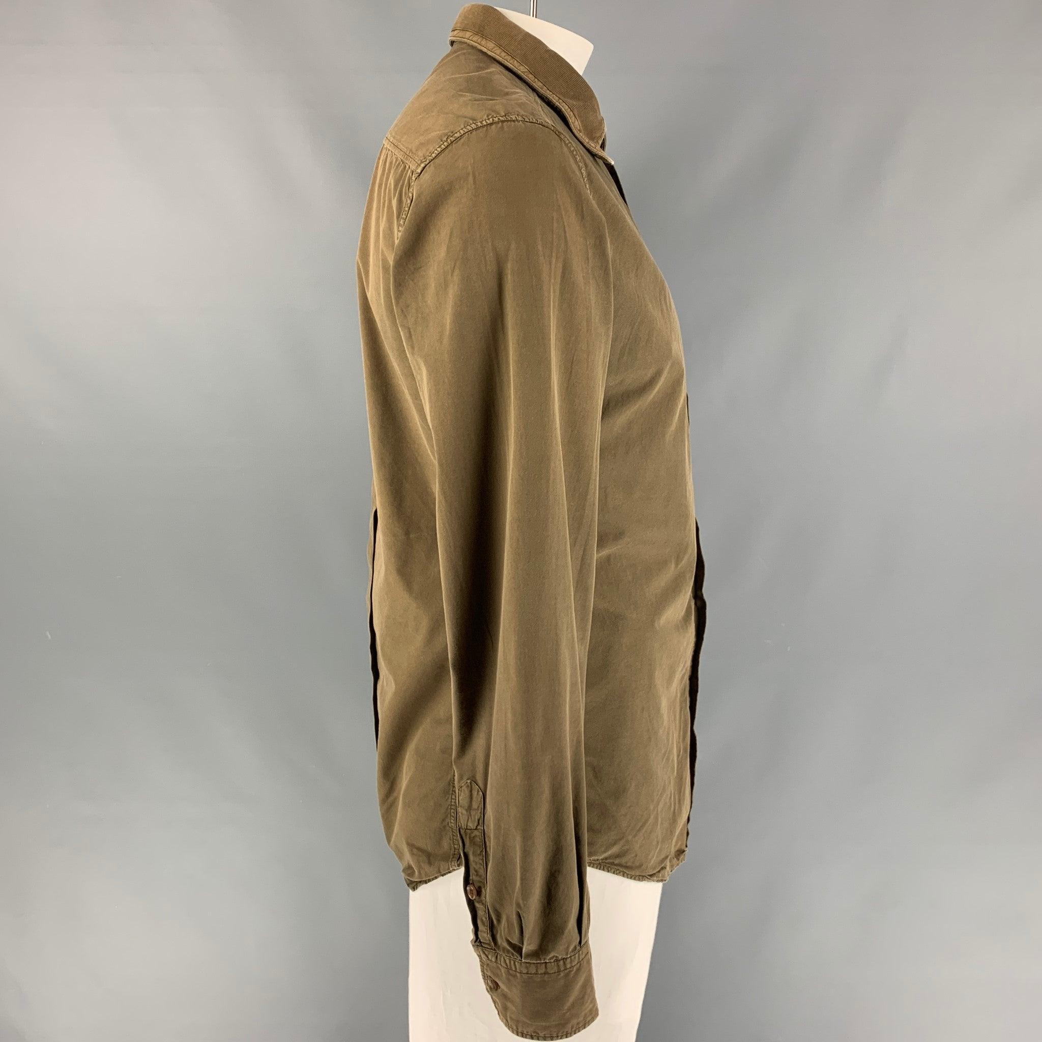 La chemise à manches longues D&G by DOLCE & GABBANA est proposée en coton marron. Elle présente un col rond à texture côtelée et se ferme par un bouton. Bon état d'origine. Signes d'usure modérés. 

Marqué :   52  

Mesures : 
 
Epaule : 28 pouces