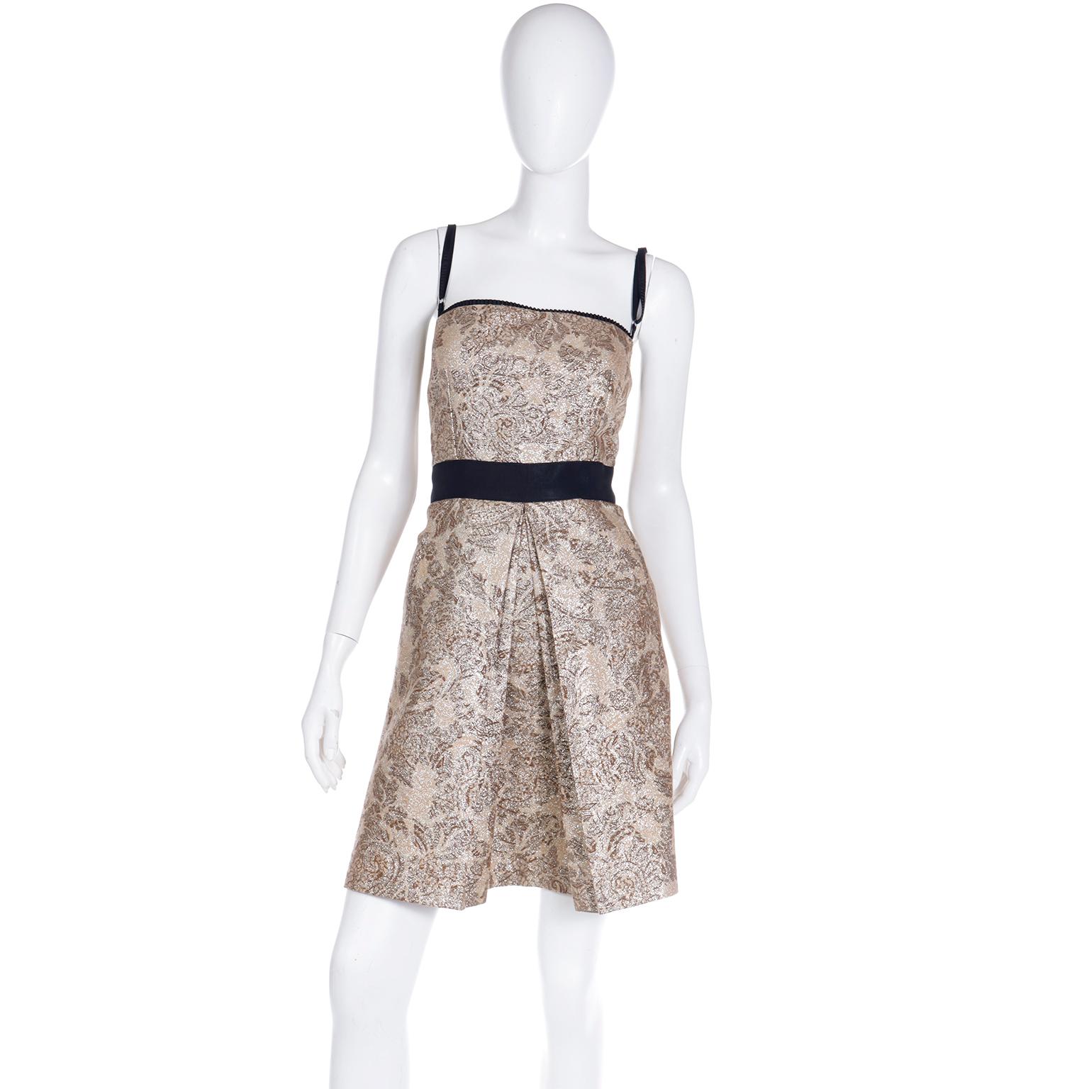 This lovely ensemble from Dolce & Gabbana includes a mini dress, coat and belt in a gold floral metallic print. The print is in subtle shades of brown and gold and the dress has black trim.  It is rare to find this outfit complete with all 3