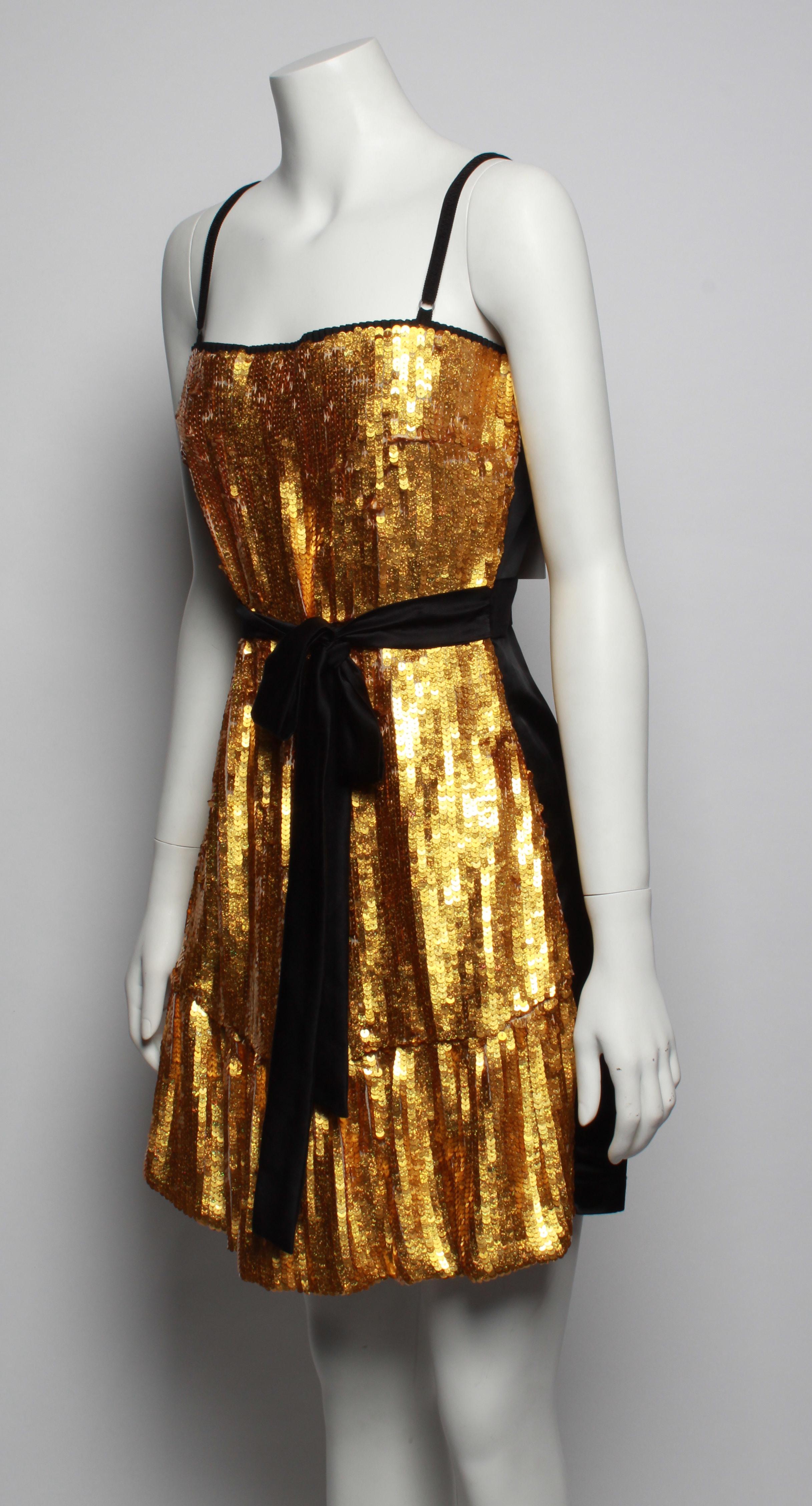 D&G Dolce & Gabbana cocktail dress features front panel in gold sequins with hem frill. Back panels and waist tie are made from luxurious black silk satin with velvet waist panel.. This dress is beautifully constructed with interior bust lining,