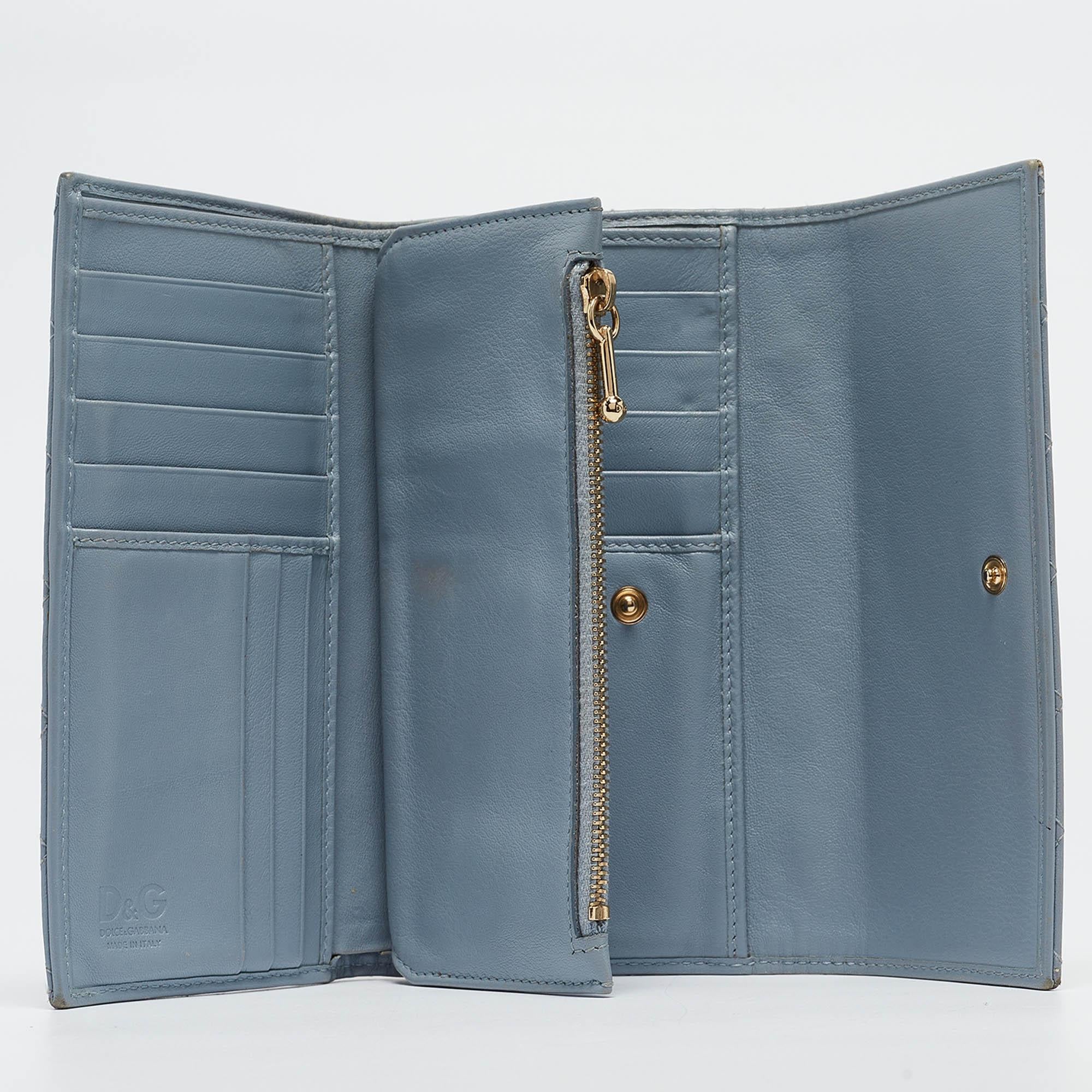 This pretty flap wallet by D & G is effortlessly designed for an elegant take. Crafted from leather, it is accented with gold-tone logo plaque on the front and is accented by a quilted pattern all over. The flap closure opens to leather and nylon