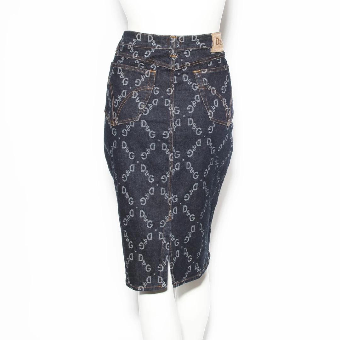 D&G by Dolce and Gabbana Skirt 
Made in Italy 
Denim 
Pencil style skirt 
D&G logo print pattern 
Dark grey button at waist zip closure 
Belt loops around waist 
Golden yellow stitch details at waist 
Fabric Composition: 98% Cotton 2% Synthetic