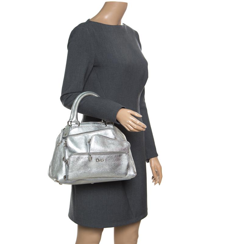 Well-made and reliable, this lovely Mindy satchel is from D&G. It has been crafted from metallic silver leather and designed with multiple zip pockets on the front. The bag, carrying a pretty shape, is equipped with a well-sized fabric-lined