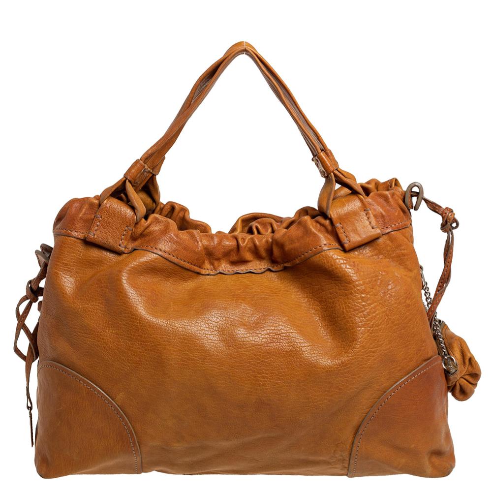 Striking and unique, this D&G Linda tote will add character to any look! Featuring a tan leather body, this bag is coupled with neat stitches. This tote also has double handles, drawstring closure, and silver-tone hardware. Lined with satin, its