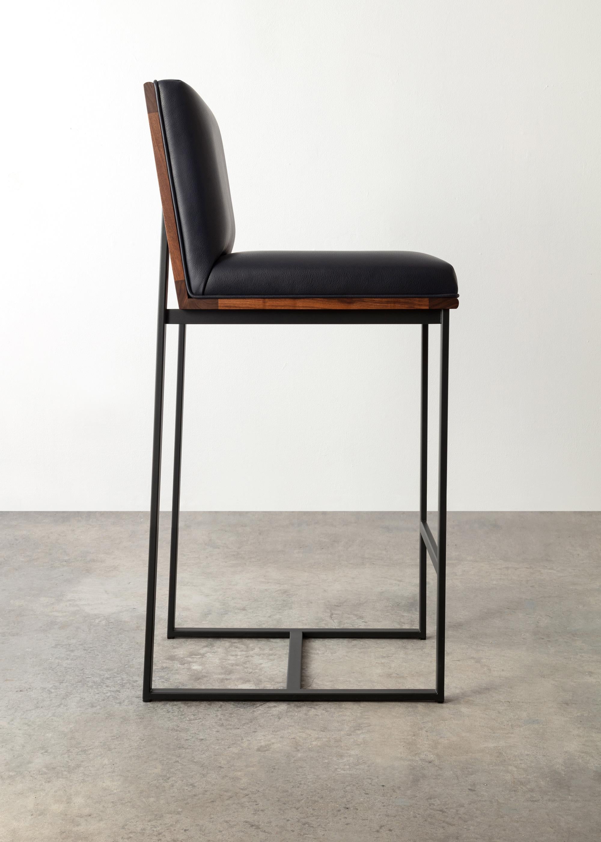 The DGD bar stool finds formality and comfort in the industrial and organic.
Shown in walnut with navy leather
Available ash, cherry, maple, walnut, or white oak. 
Powder coated steel frame shown in matte black and available in standard RAL colors.
