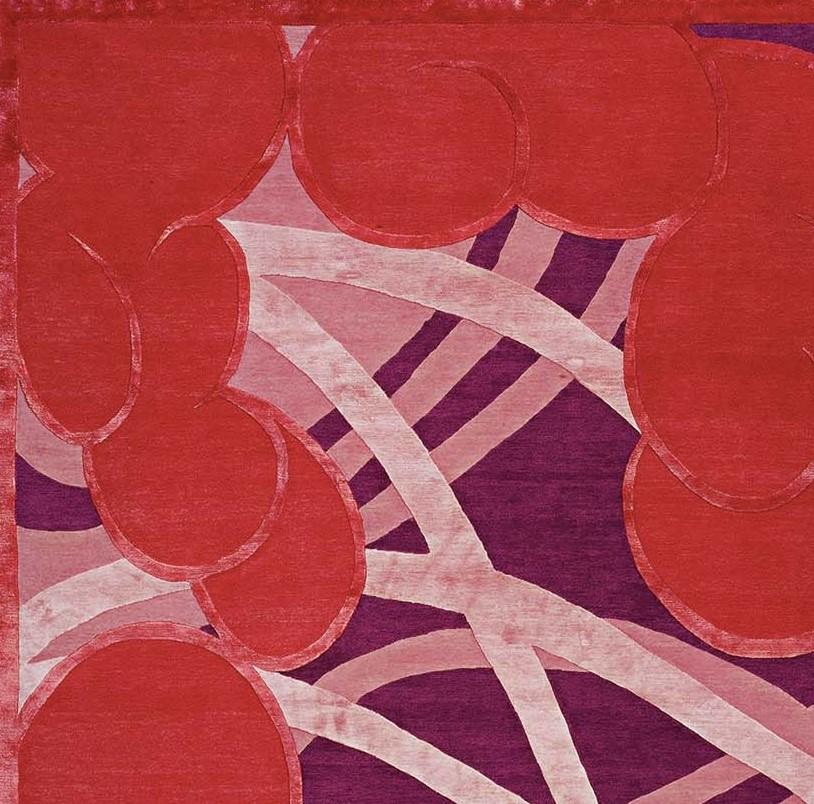 Dieser exquisite Teppich, der an Pop-Art-Designs mit traditionellen japanischen Druckelementen erinnert, zeichnet sich durch kräftige Farben aus, die die geschwungenen Formen, die über den violetten Hintergrund tanzen, hervorheben. Kräftige rote