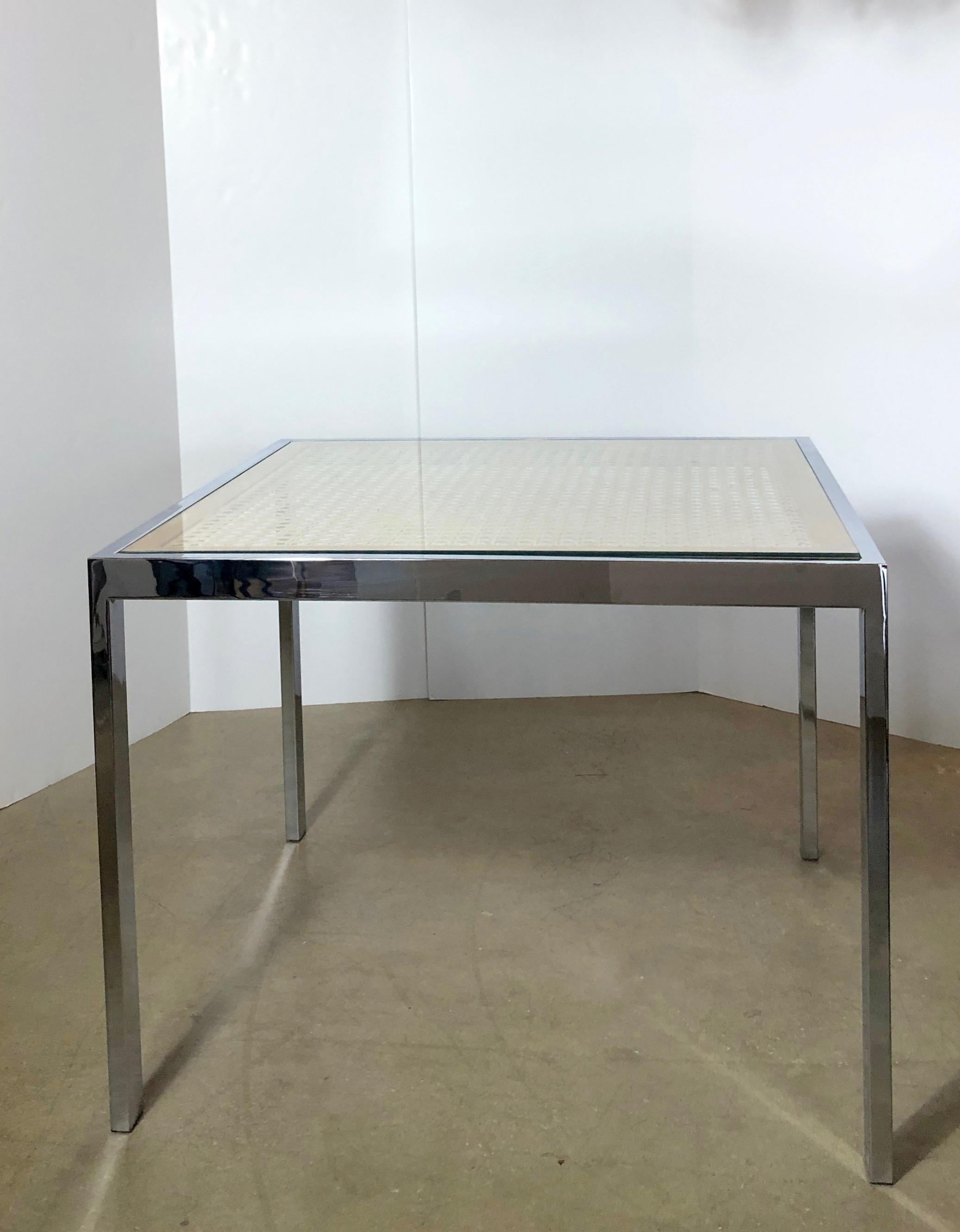 Offered is a Mid-Century Modern glass over tan wicker top with chrome plate frame game table or small dining table for Design Institute of America. This table consists of a square chrome base with inset light tan wood frame boarding a woven wicker