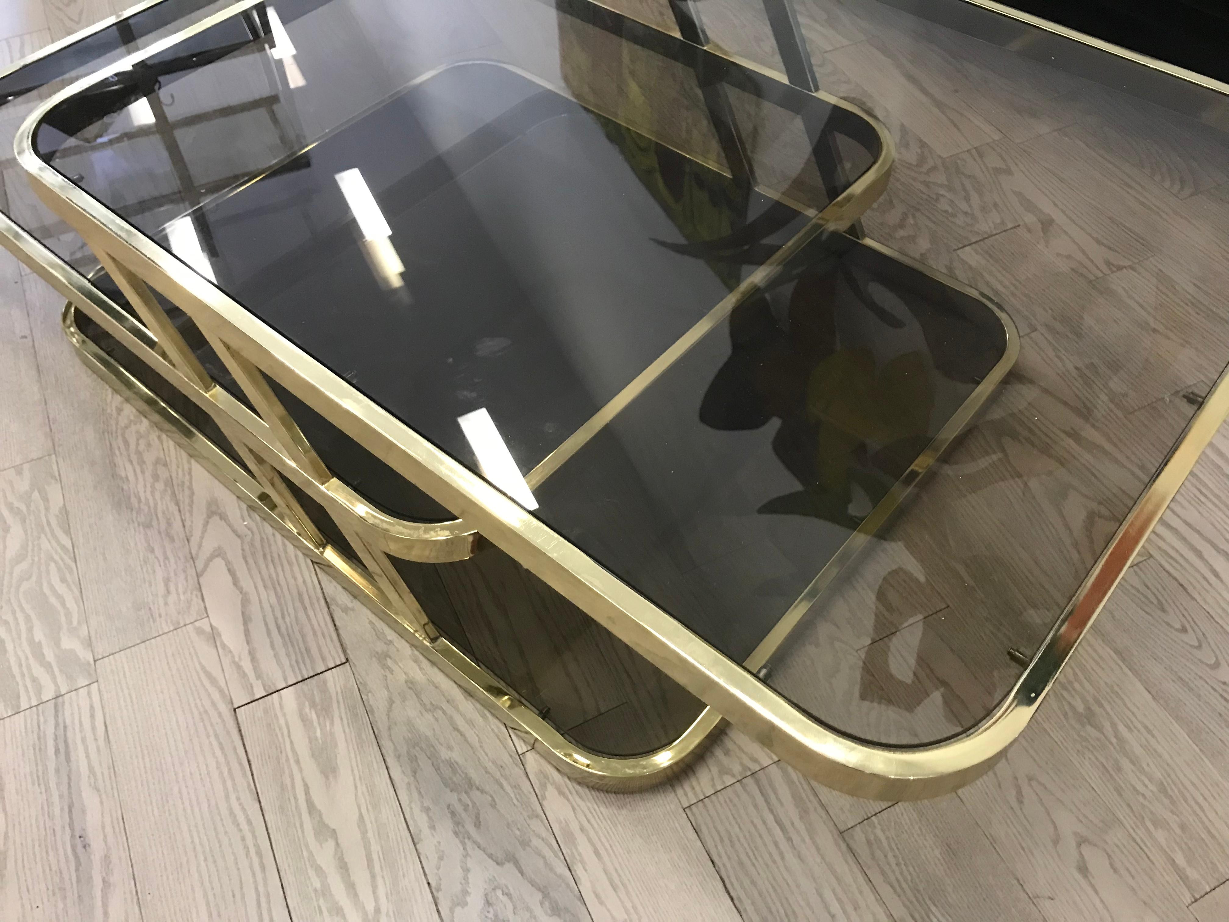 This is a nice coffee table with 3 levels and brass colored metal. Design Institute Of America. The shelves are a Smokey color glass. It looks nice with the warm brass finish.