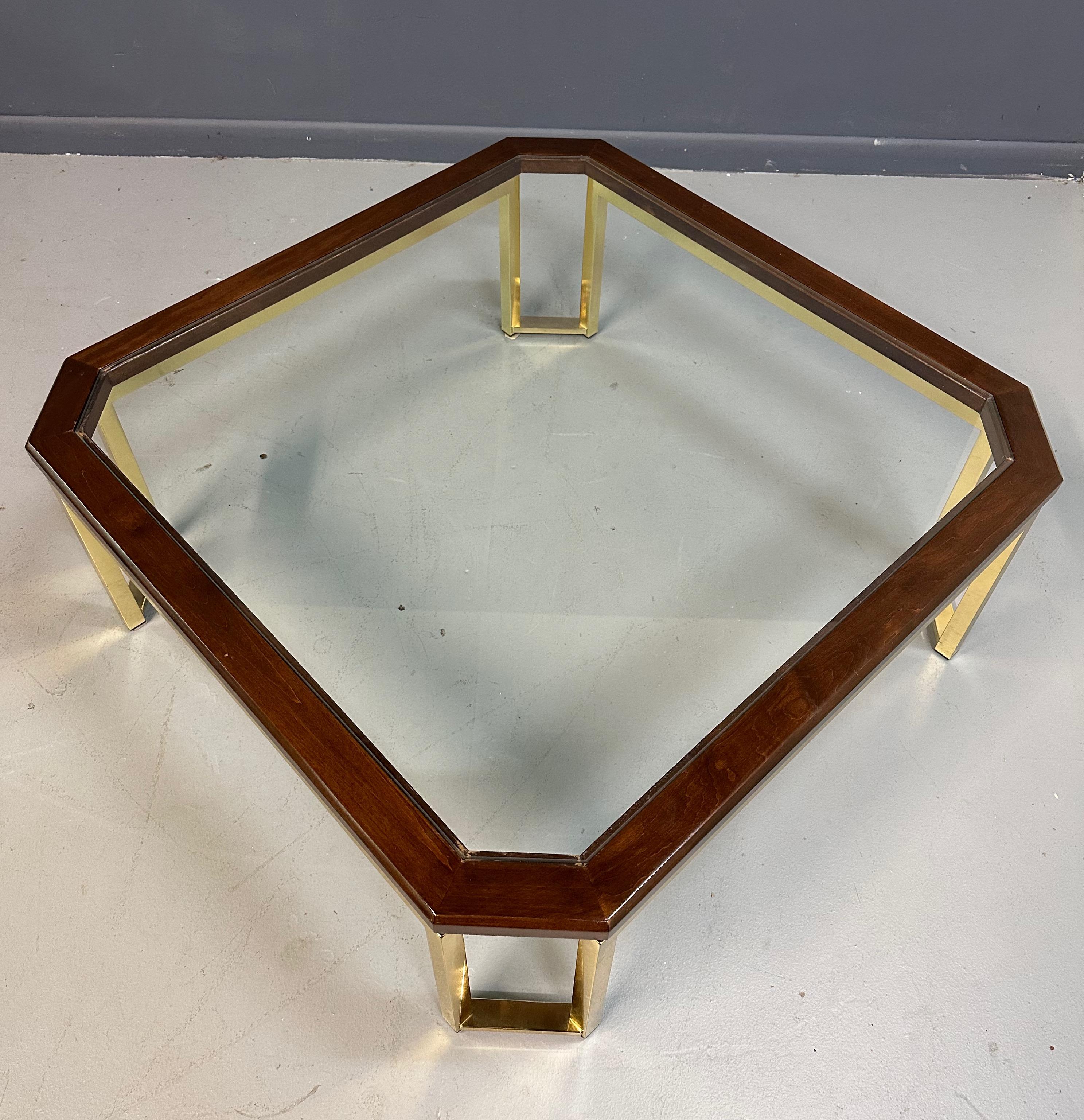 Quintessential modern designed table by the wonderful firm of Design Institute of America. This table features a mahogany surround sitting on a brass base with glass in the center. The brass tubes that circle the entire piece and lift the wood above
