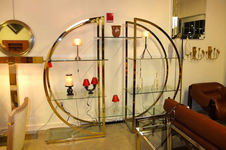 1970's Design Institute of America (DIA) pair of half circle D form brass etageres with glass shelves. Can be configured together or independently depending on your architectural statement.
Original design contemplates two center glass shelves