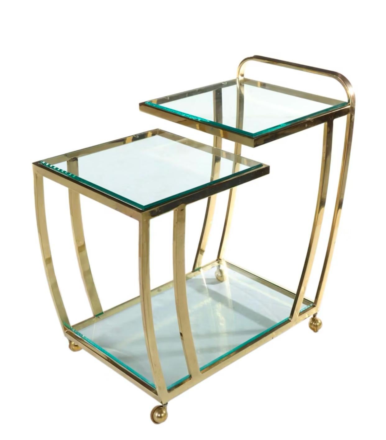 Chariot de bar mobile à deux niveaux en laiton et verre biseauté par Design Institute of America. La patine du laiton peut être laissée telle quelle ou polie à la demande du client. Pas de frais supplémentaires. 