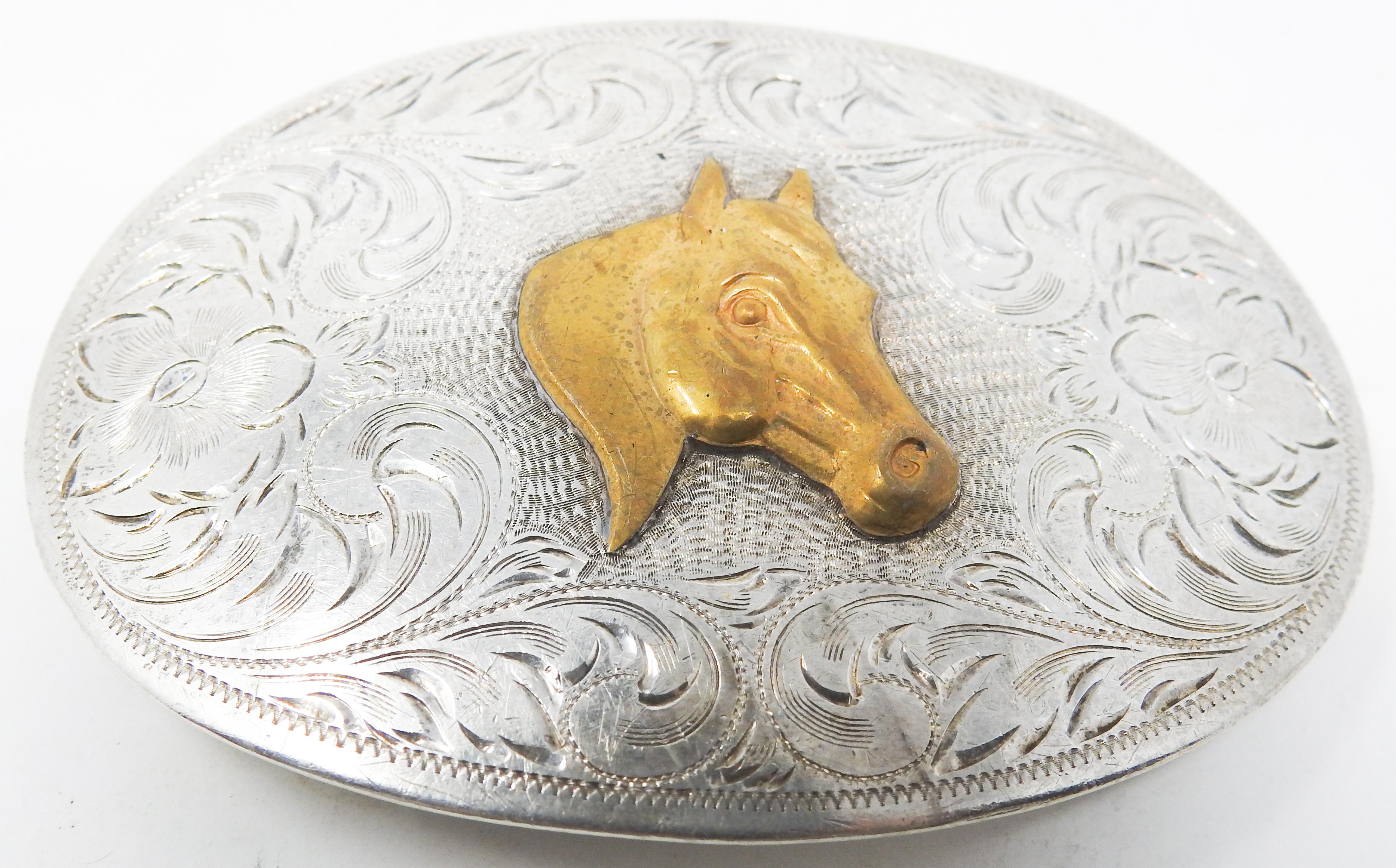 Offering this handsome Diablo sterling silver with brass horse head belt buckle. The front of the buckle has some floral and scrollwork engraved filigree. In the center is a solid brass horse head. The back of the buckle has all the working parts.