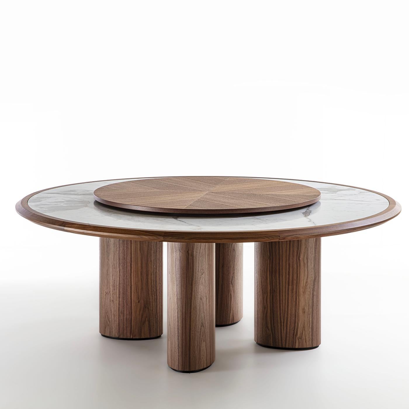 El encanto espontáneo de los materiales naturales se une en esta mesa al impacto visual de audaces volúmenes geométricos. Fabricada en nogal Canaletto macizo, la estructura ostenta un rico veteado que puede admirarse desde las patas de corte