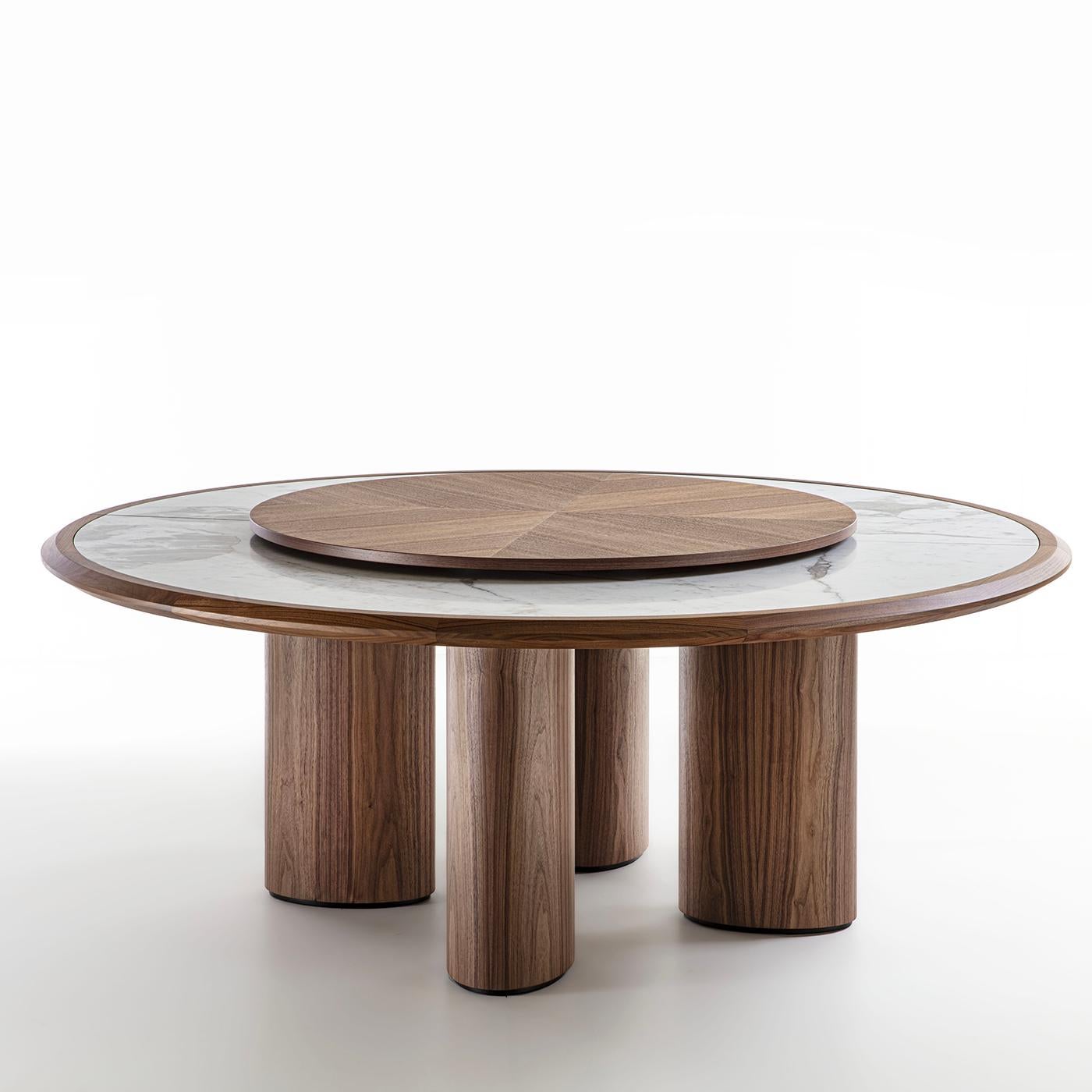 The spontaneous charm of natural materials meets in this table the visual impact of bold geometric volumes. Fashioned of solid Canaletto walnut, the structure boasts a rich grain that can be admired from the elliptic-cut legs to the circular frame