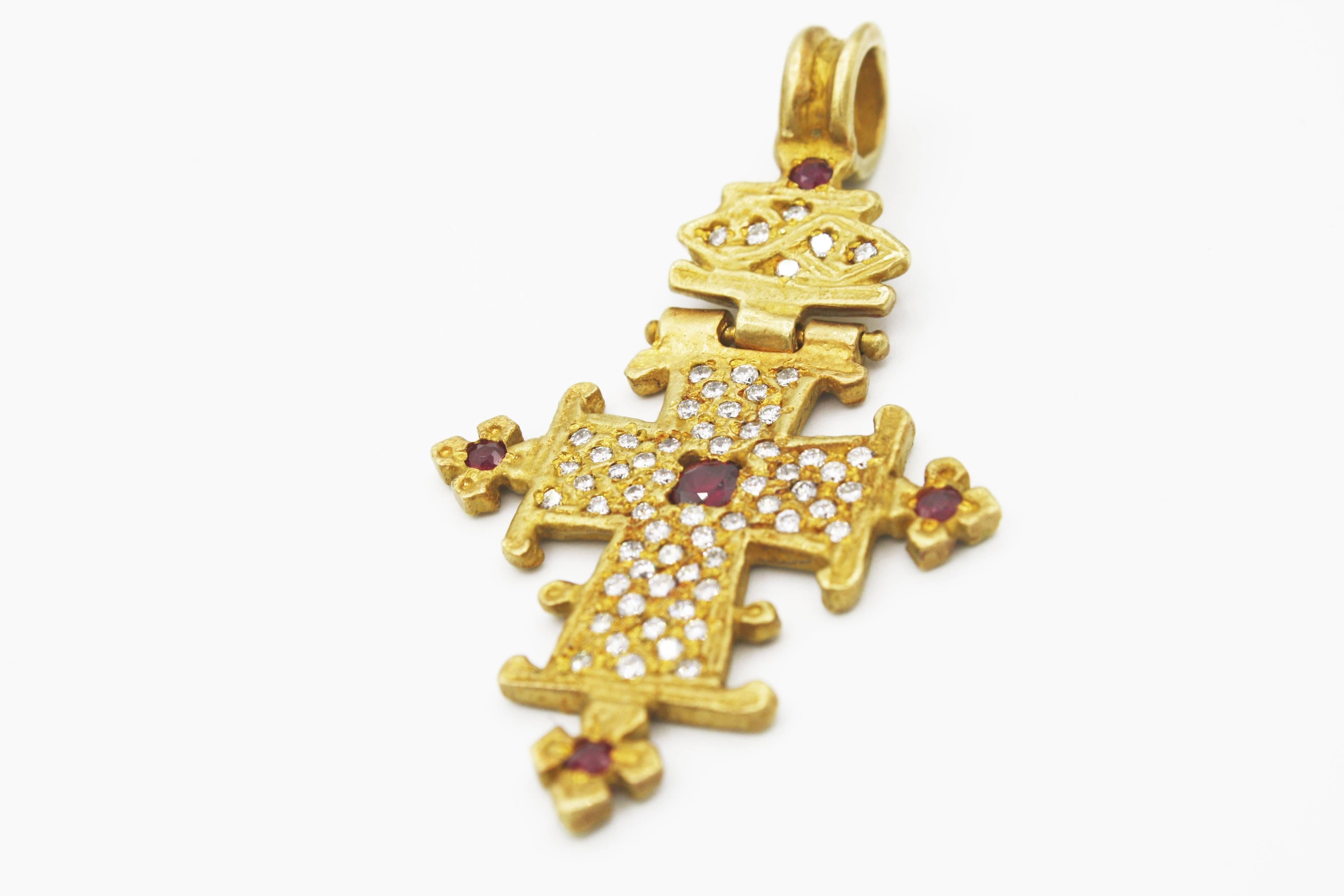 This eye catching Renato Cipullo 18k yellow gold cross pendant features 69 .70ct diamonds and 4 .32ct rubies with a delicate hinge allowing the cross and loop to flex.